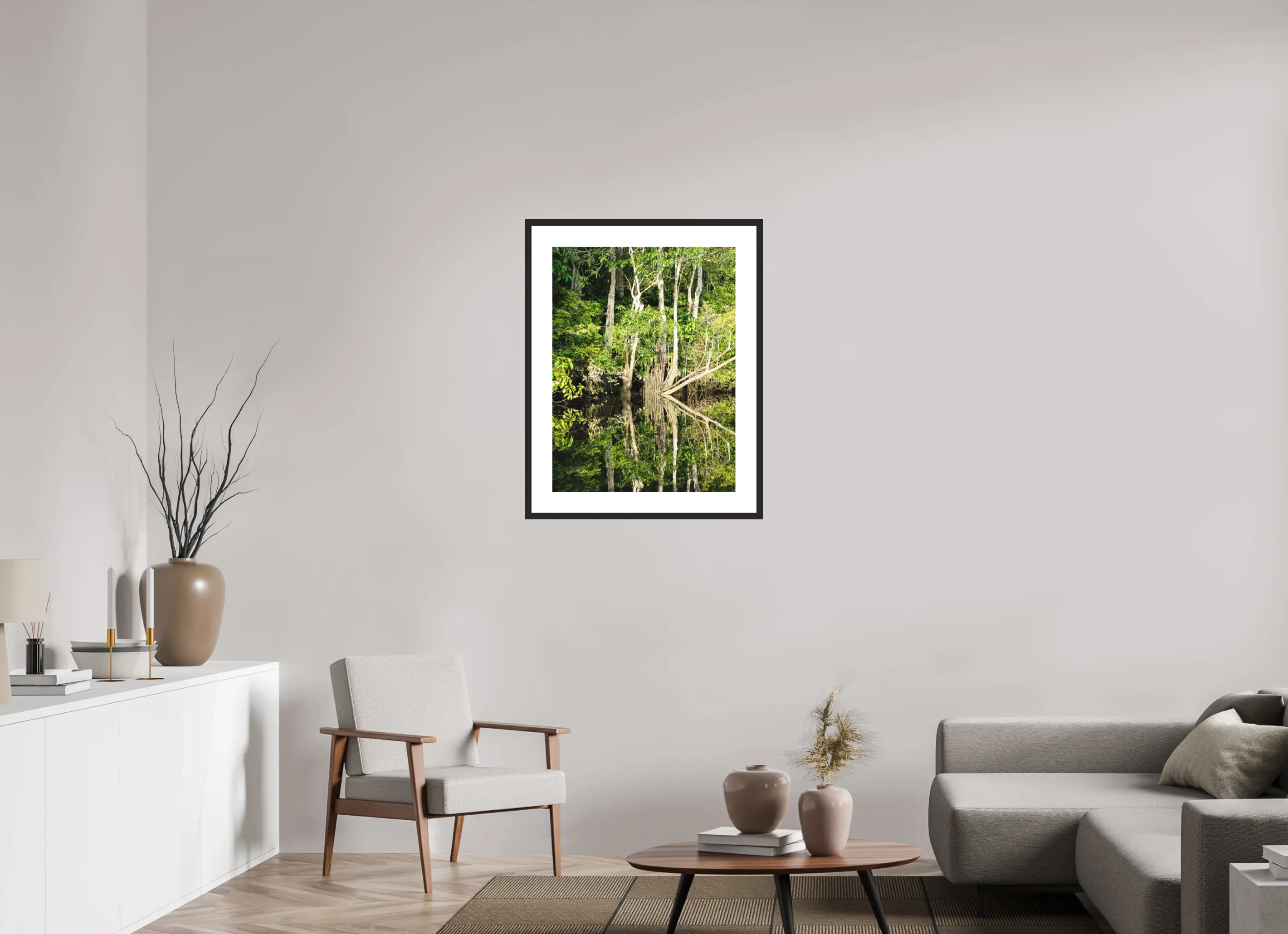 Fine art print “The Jungle Mirror” featuring dense Bornean rainforest trees perfectly reflected in still dark river water, displayed in a passepartout frame in a modern living room setting.