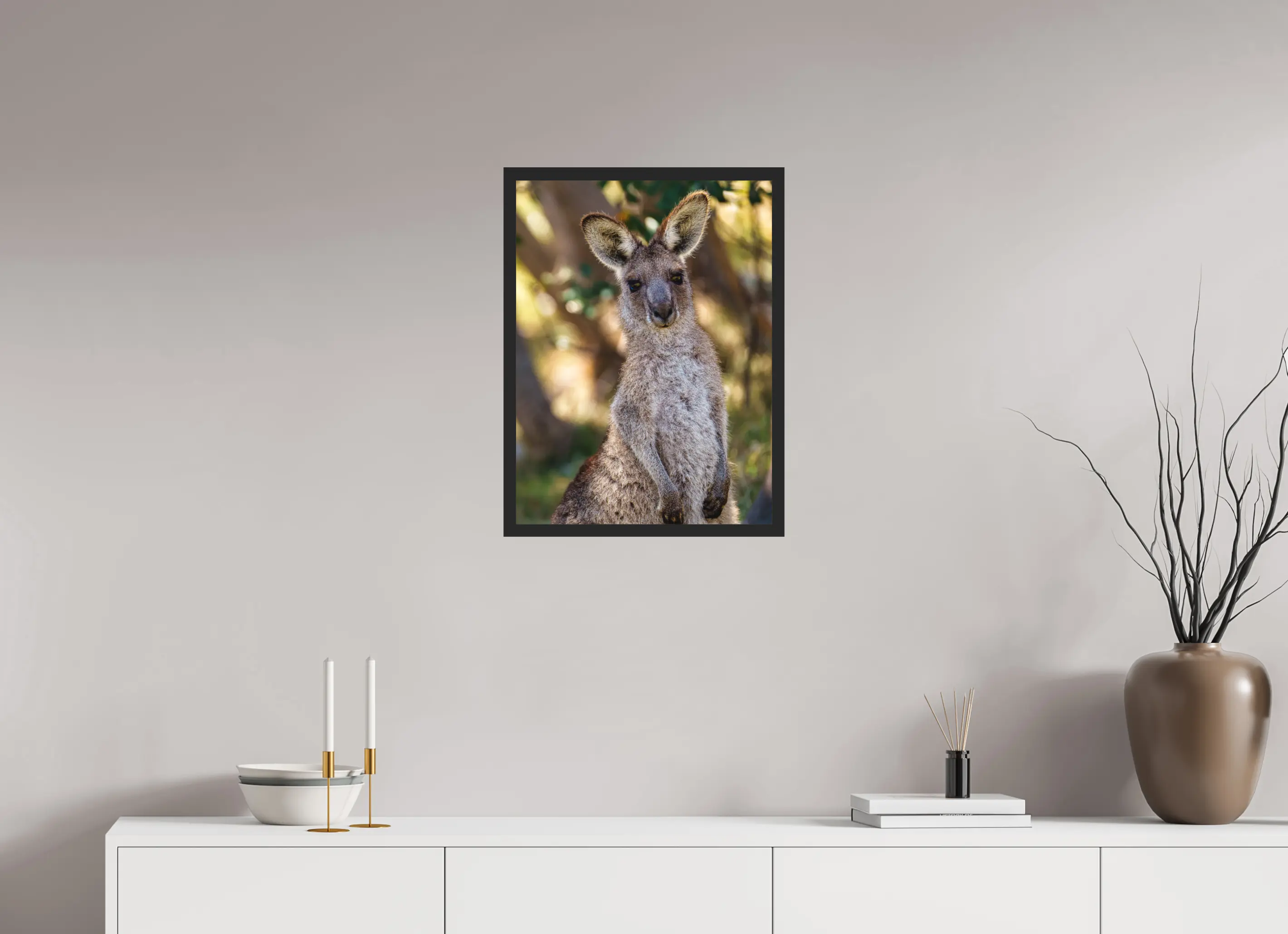 Fine art print “Curious Glance” featuring a wallaby standing alert in the Australian bush with warm sunlight filtering through the trees, displayed classic framed in a modern living room setting.