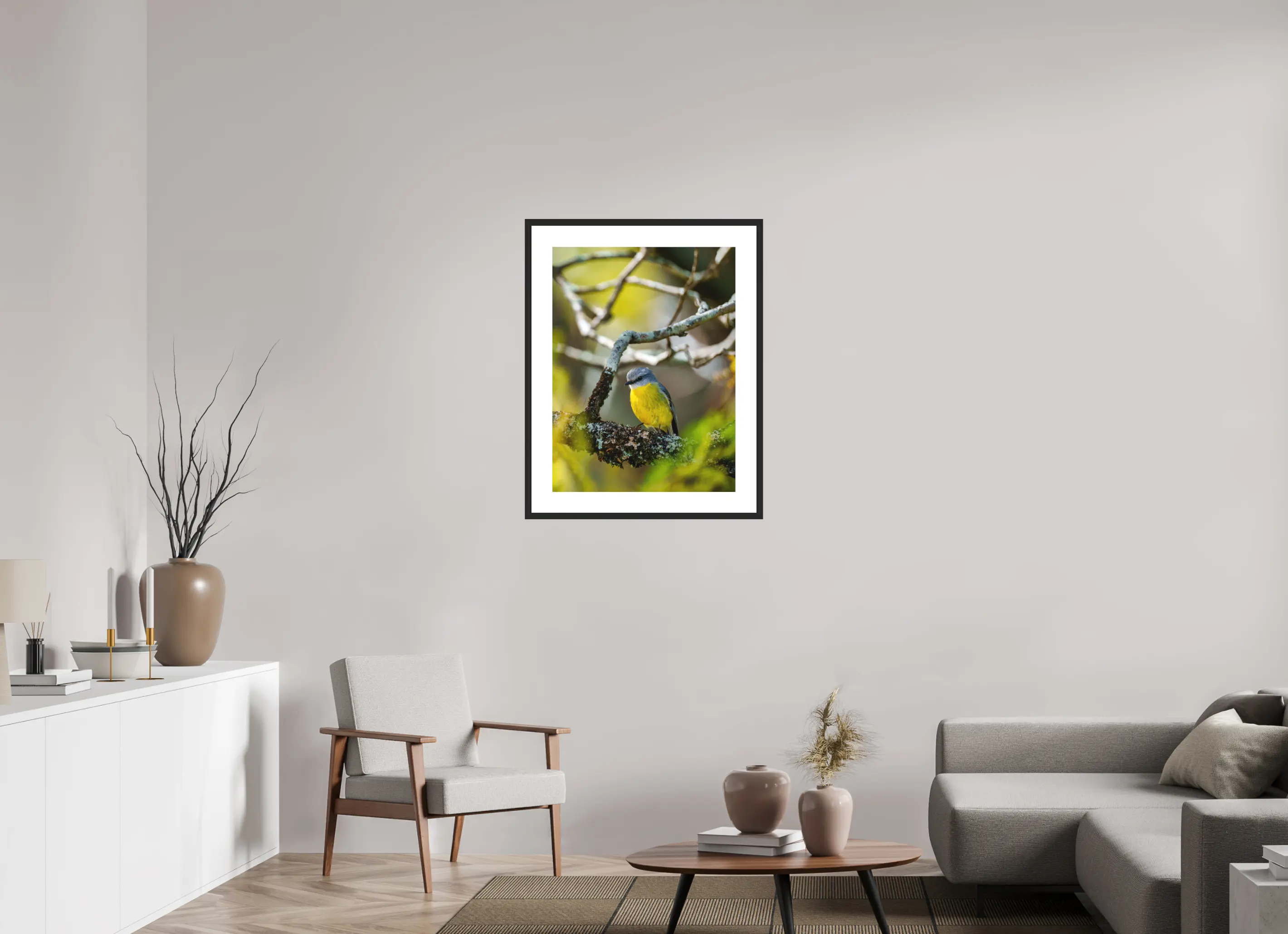 Fine art print “Glimpse of Gold” featuring a eastern yellow robin surrounded by soft green and golden light, displayed in a passepartout frame in a modern living room setting.