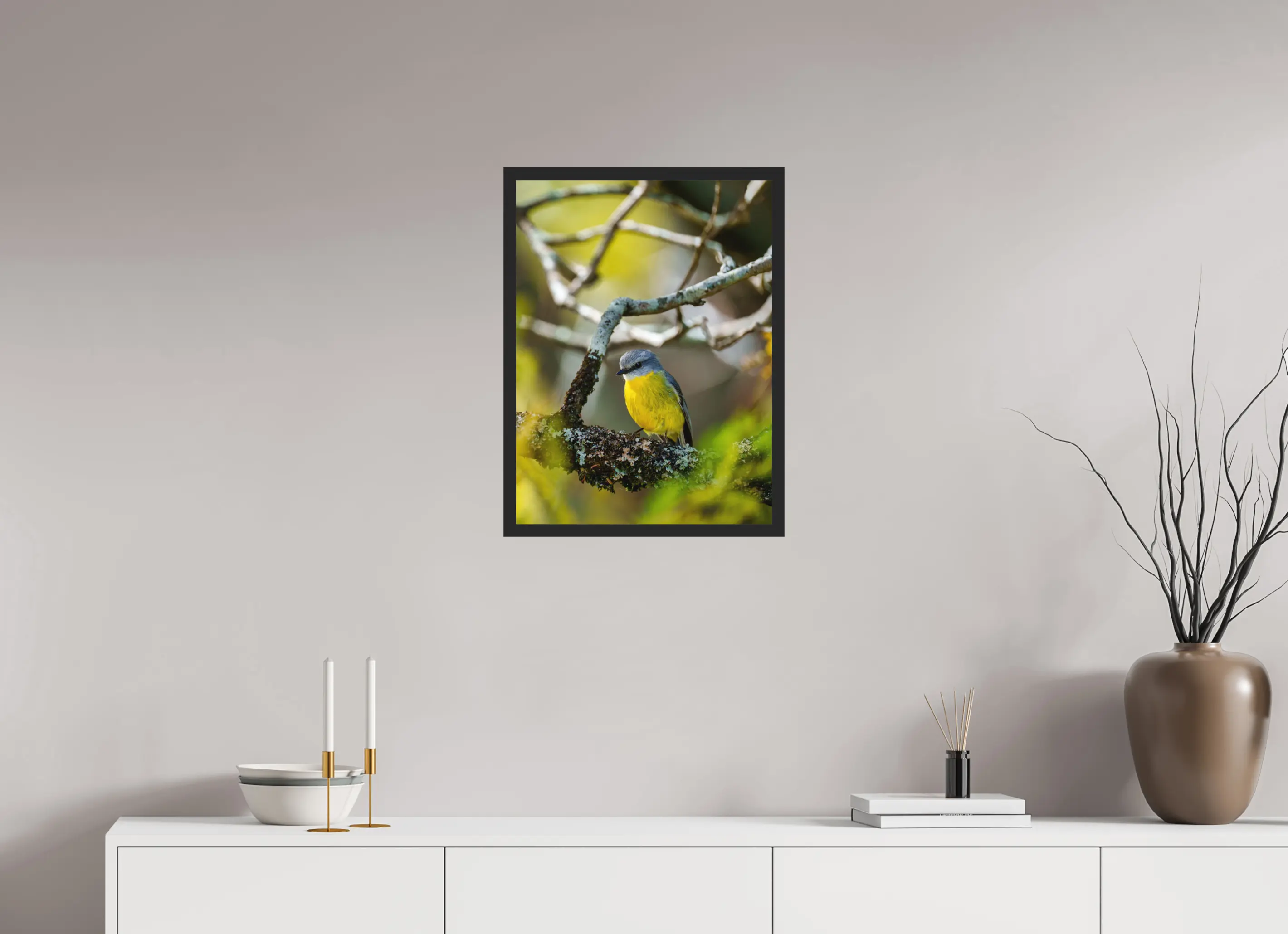 Fine art print “Glimpse of Gold” featuring a eastern yellow robin surrounded by soft green and golden light, displayed classic framed in a modern living room setting.