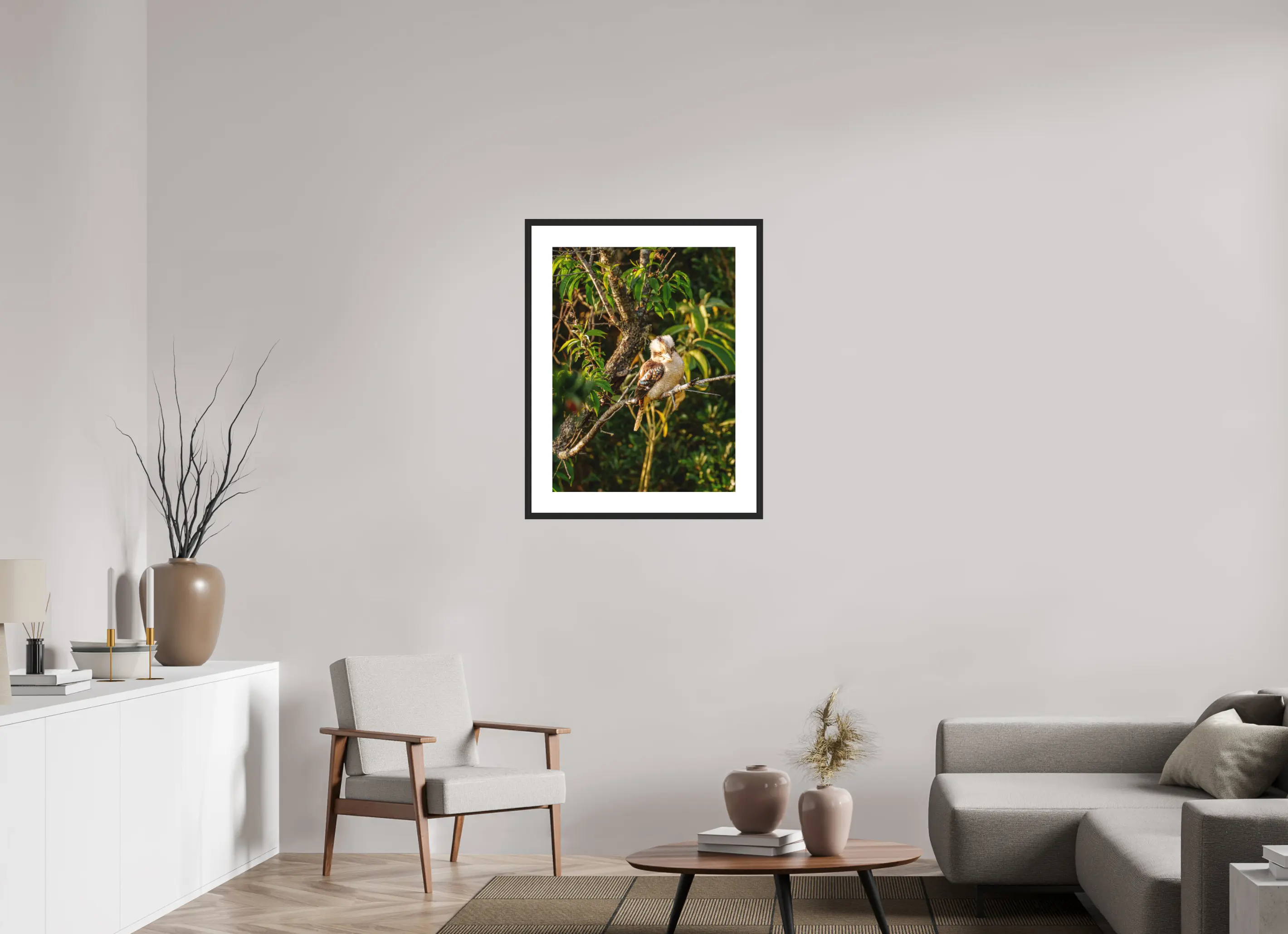 Fine art print “Laughter of the Forest” featuring a laughing kookaburra surrounded by green foliage in warm afternoon light, displayed in a passepartout frame in a modern living room setting.