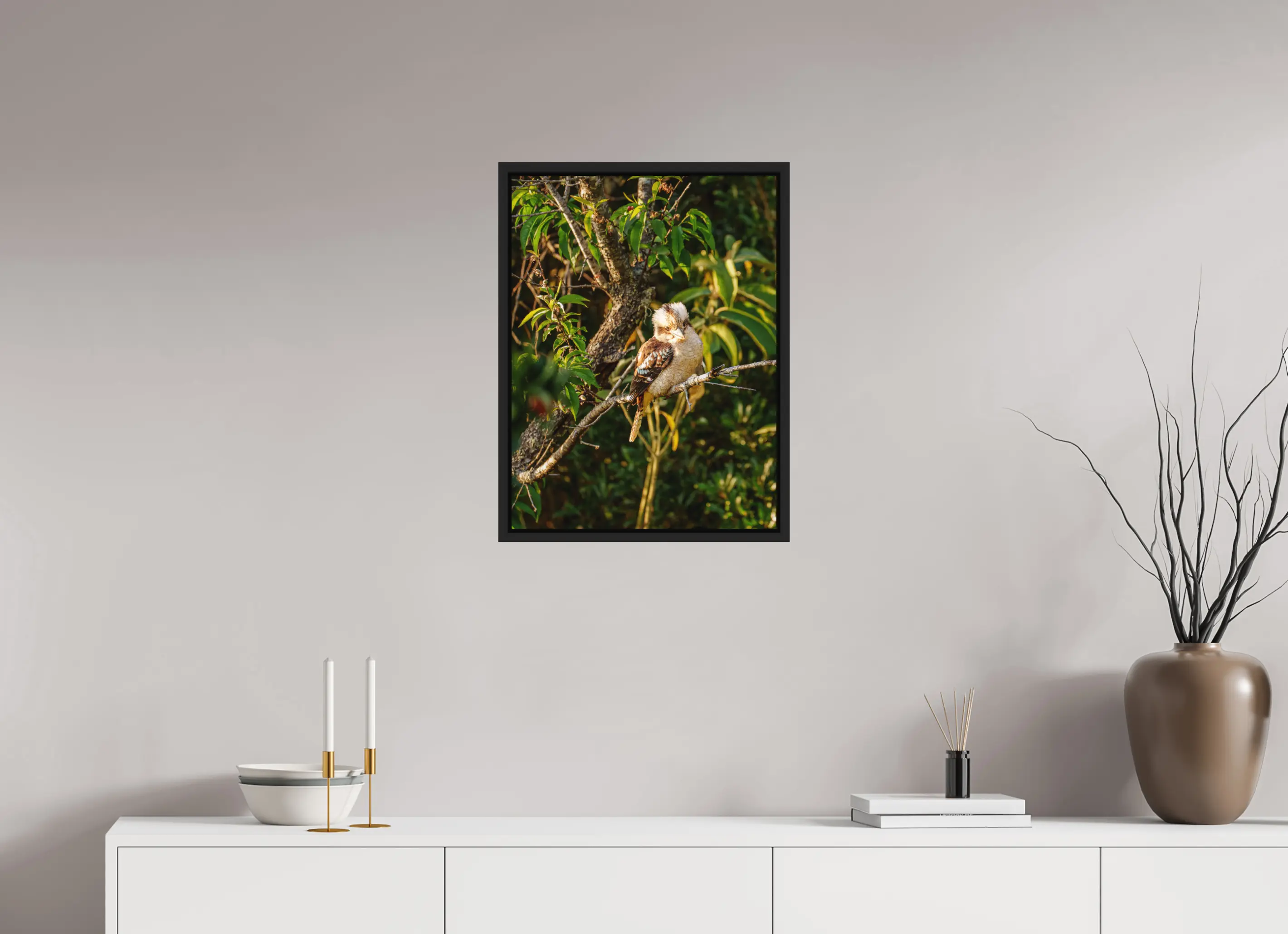 Fine art print “Laughter of the Forest” featuring a laughing kookaburra surrounded by green foliage in warm afternoon light, displayed in a floater frame in a modern living room setting.