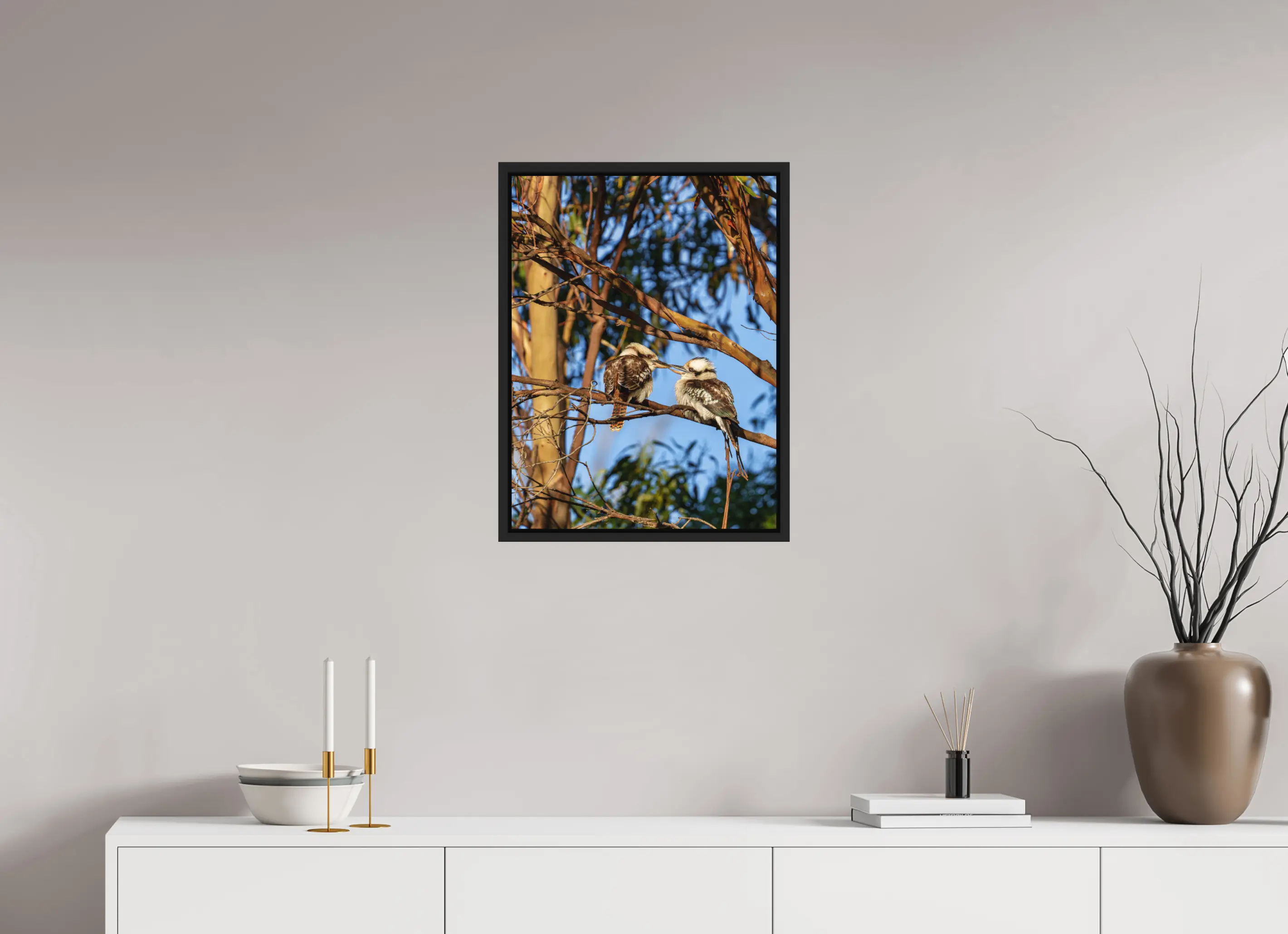 Fine art print “Loving Kookaburras” featuring two kookaburras on a eucalyptus branch sharing a tender moment, displayed in a floater frame in a modern living room setting.