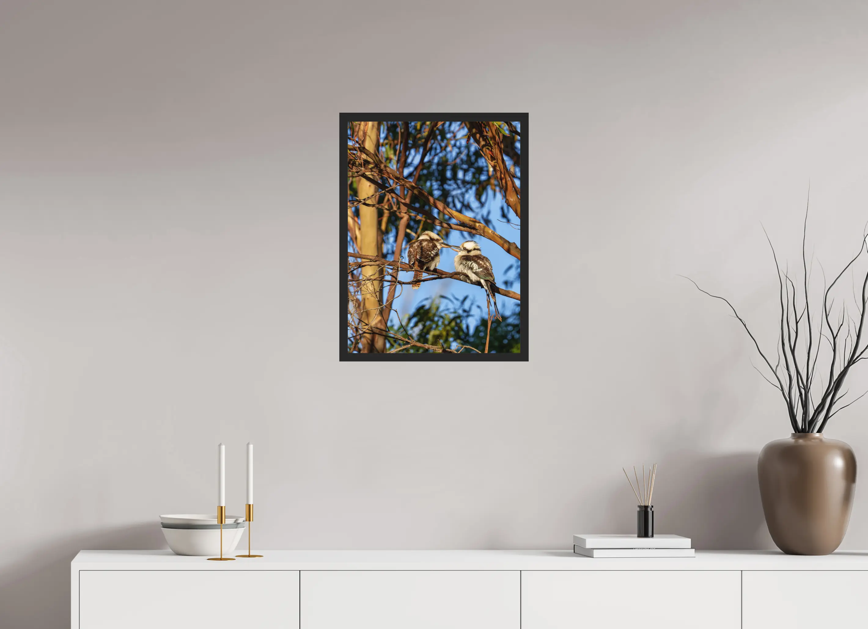 Fine art print “Loving Kookaburras” featuring two kookaburras on a eucalyptus branch sharing a tender moment, displayed classic framed in a modern living room setting.