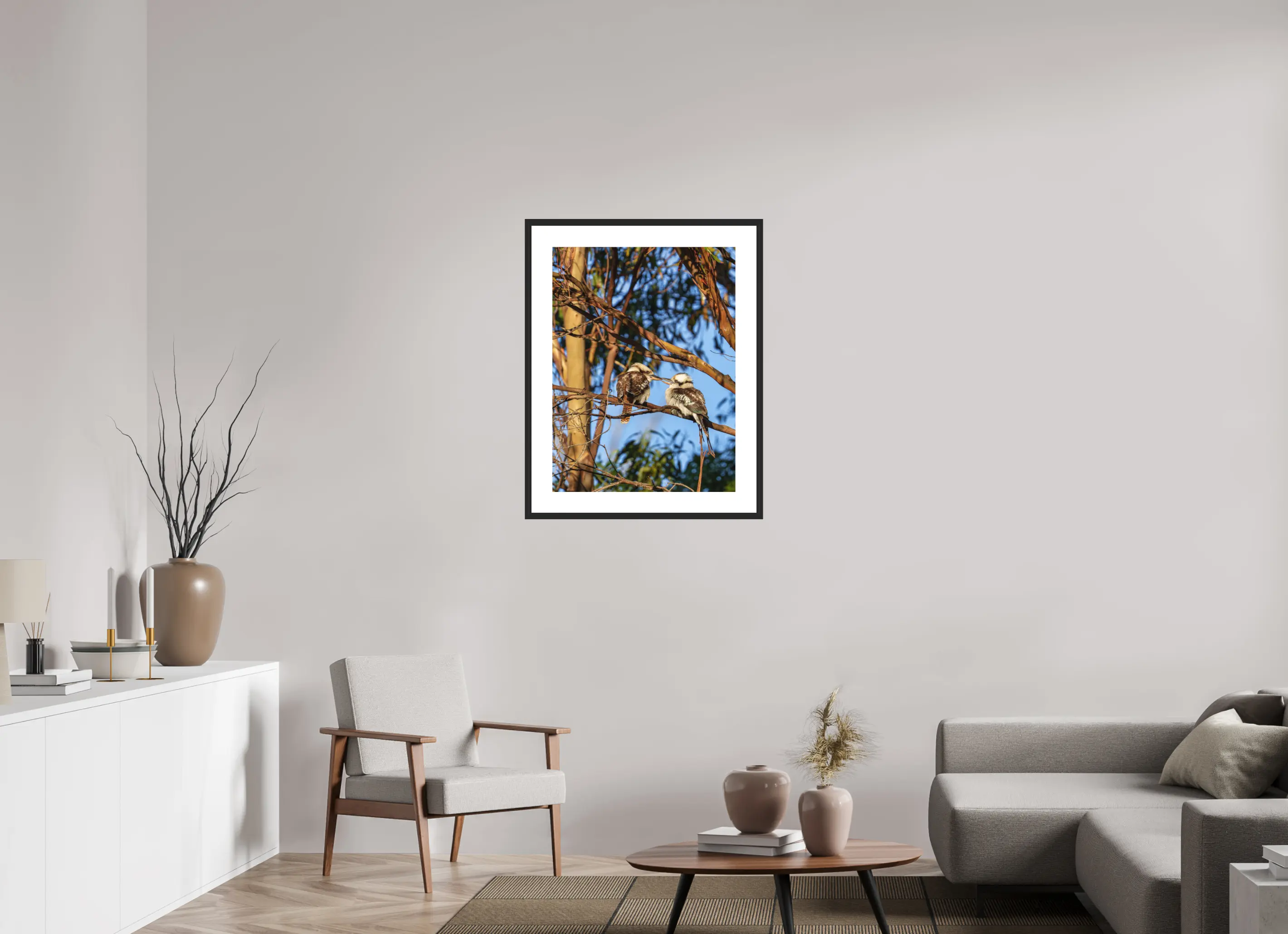 Fine art print “Loving Kookaburras” featuring two kookaburras on a eucalyptus branch sharing a tender moment, displayed in a passepartout frame in a modern living room setting.