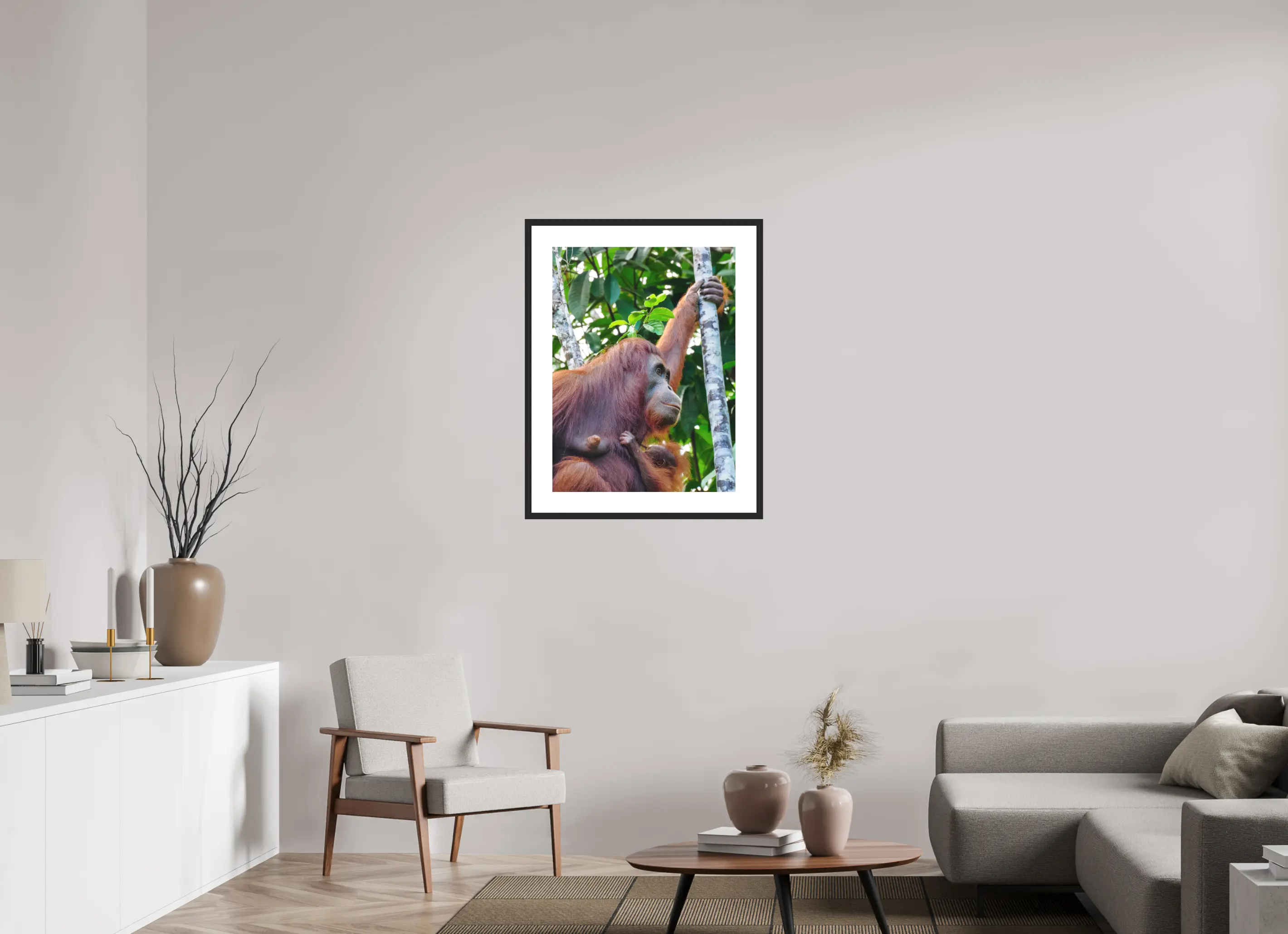 Fine art print “Motherhood” featuring a orangutan holding her baby in the tropical rainforest canopy of Borneo, displayed in a passepartout frame in a modern living room setting.