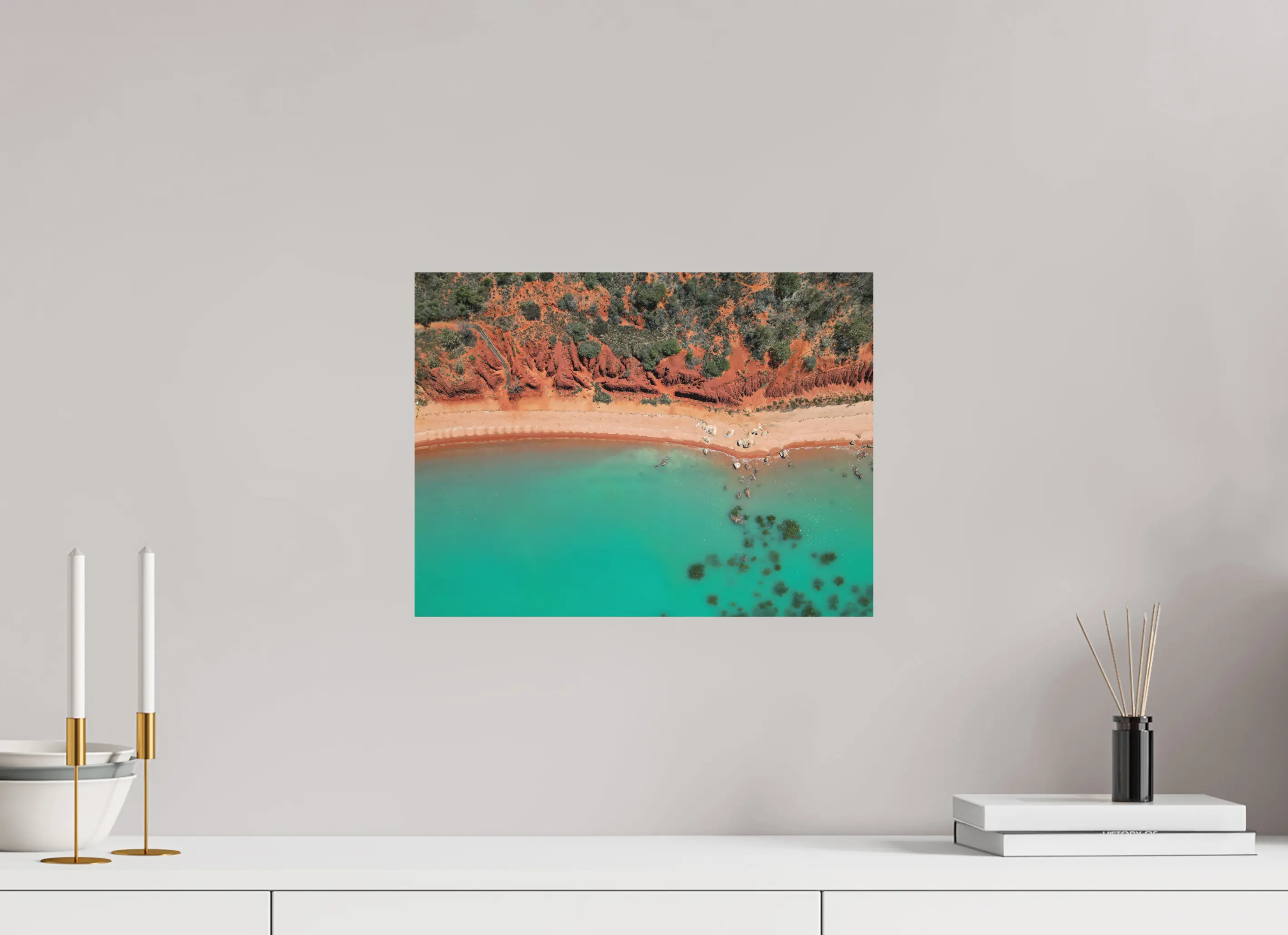 Fine art print “Painted by Nature” featuring an aerial view of red cliffs and turquoise waters meeting along the coast of Broome Western Australia, displayed on aluminium dibond in a modern living room setting.