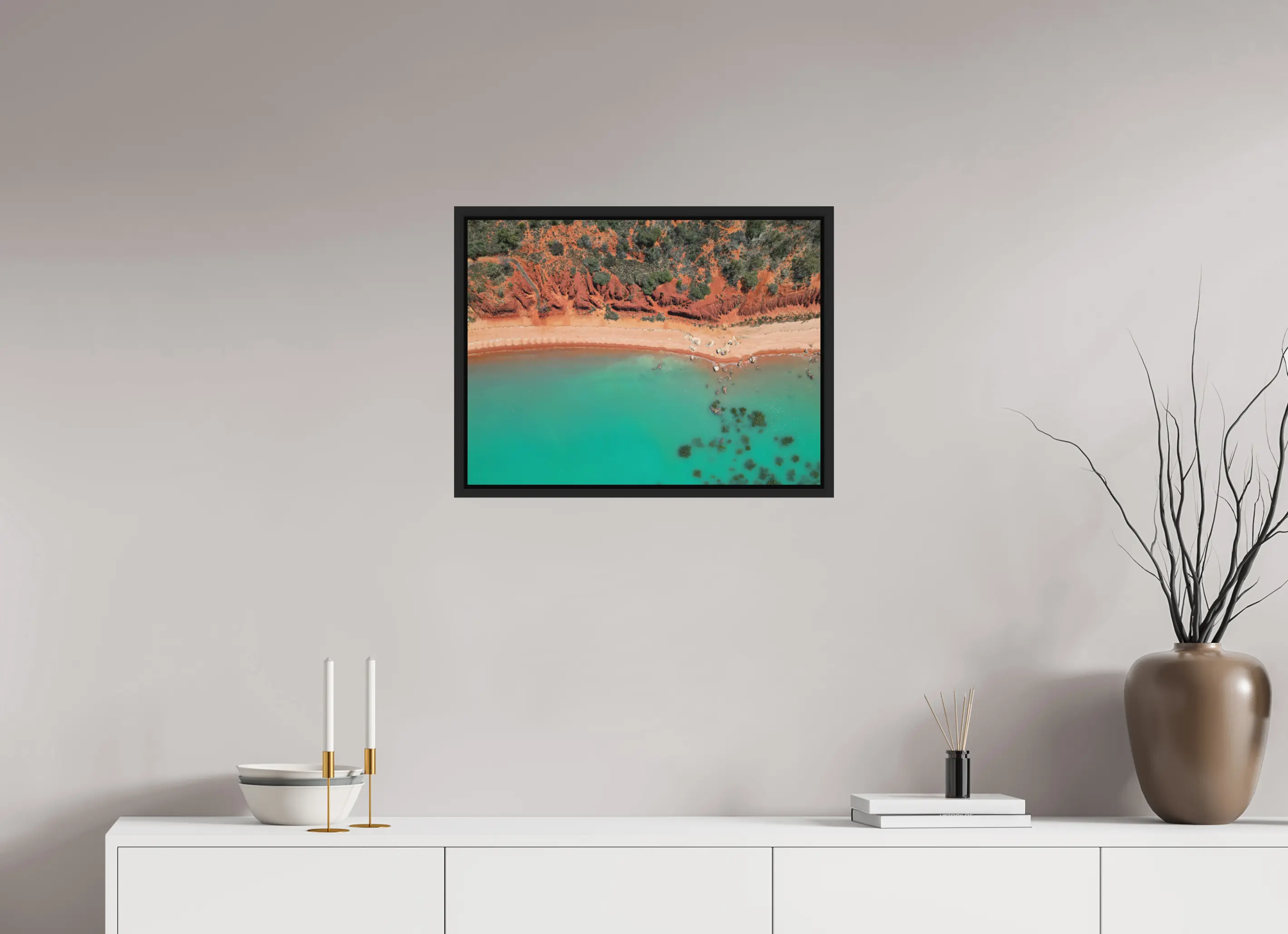Fine art print “Painted by Nature” featuring an aerial view of red cliffs and turquoise waters meeting along the coast of Broome Western Australia, displayed in a floater frame in a modern living room setting.