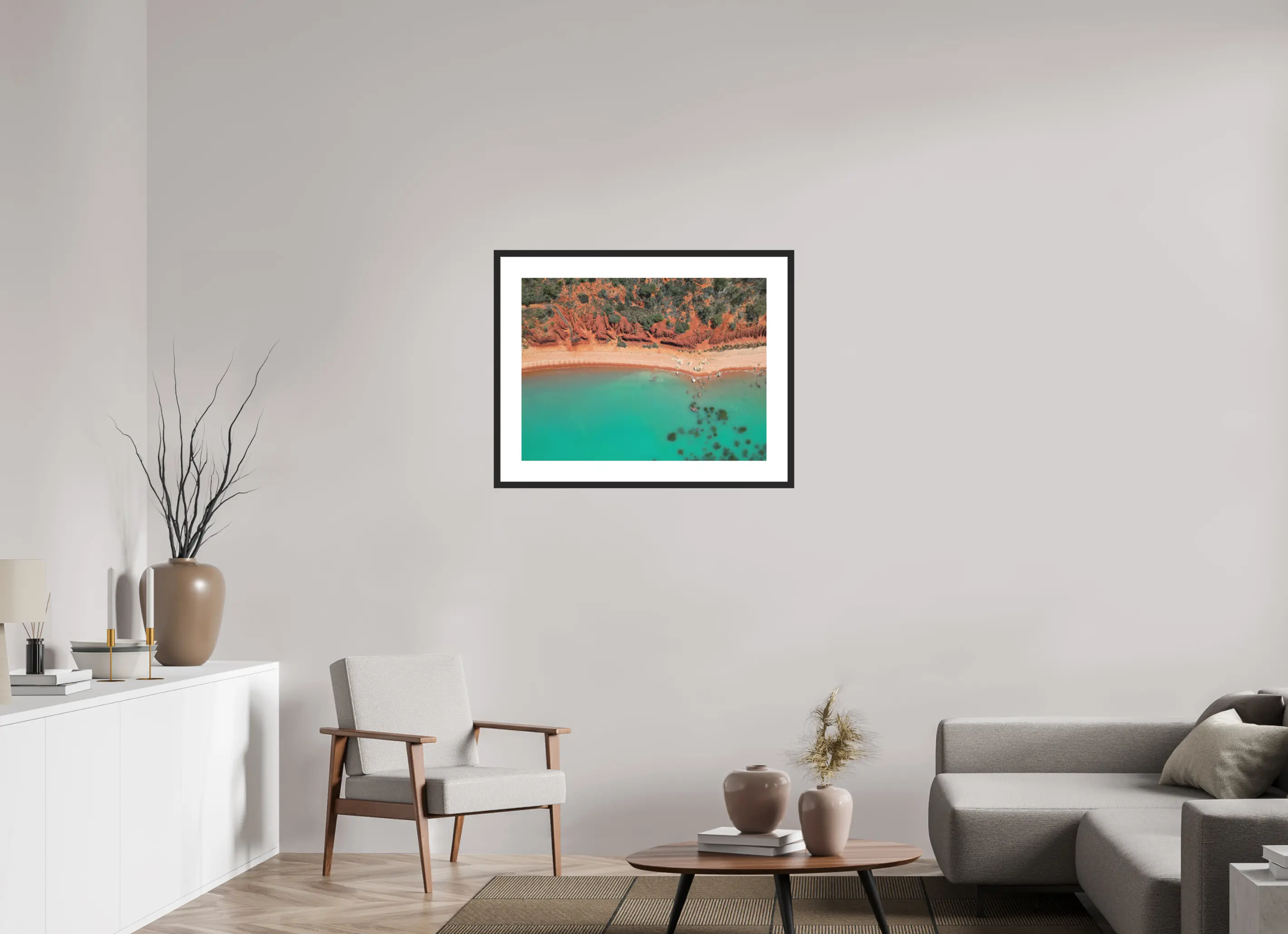 Fine art print “Painted by Nature” featuring an aerial view of red cliffs and turquoise waters meeting along the coast of Broome Western Australia, displayed in a passepartout frame in a modern living room setting.