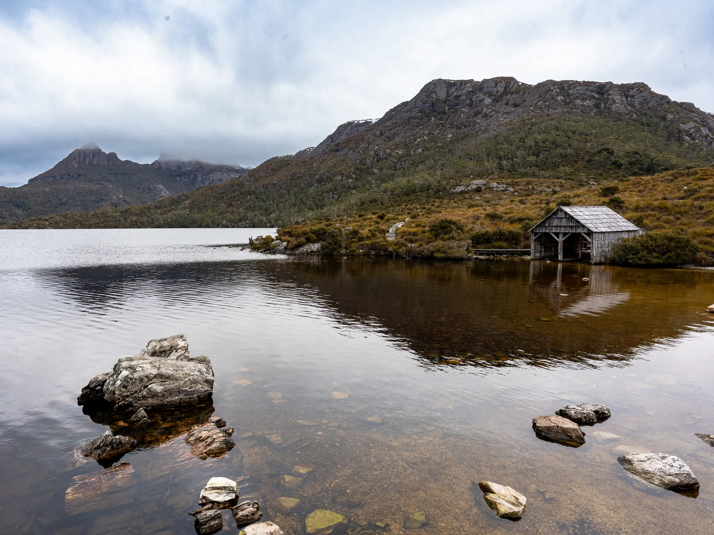 Wooden boathouse on the calm waters of Dove Lake beneath Cradle Mountain in Tasmania.