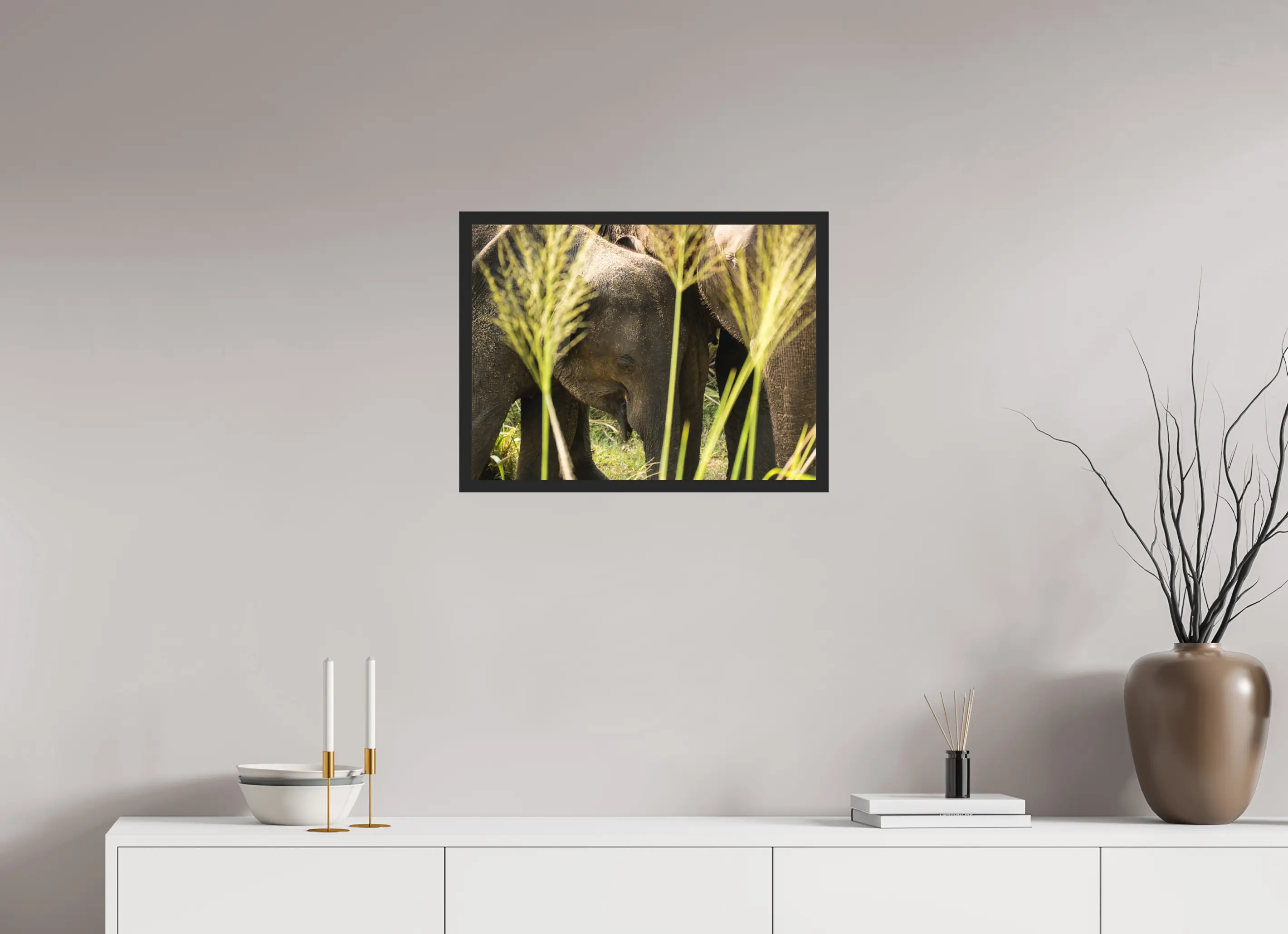 Fine art print “Protection of the Herd” featuring a group of Asian elephants huddled closely together in the tall grasslands of Sri Lanka, displayed in a floater frame in a modern living room setting.Fine art print “Protection of the Herd” featuring a grou