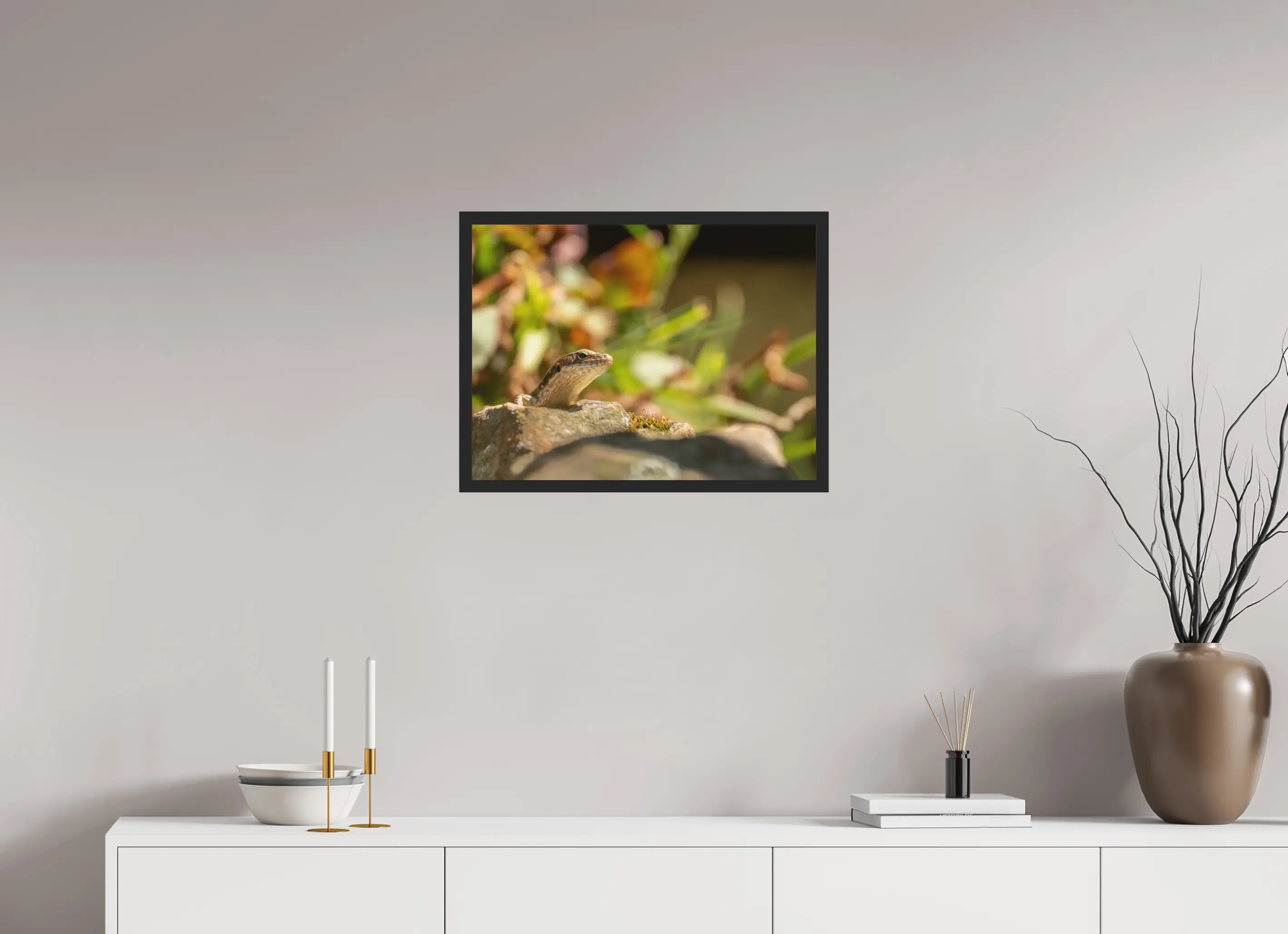 Fine art print “Rest” featuring a Lizard basking in the sunlight on a warm rock surrounded by soft blurred greenery, displayed classic framed in a modern living room setting.