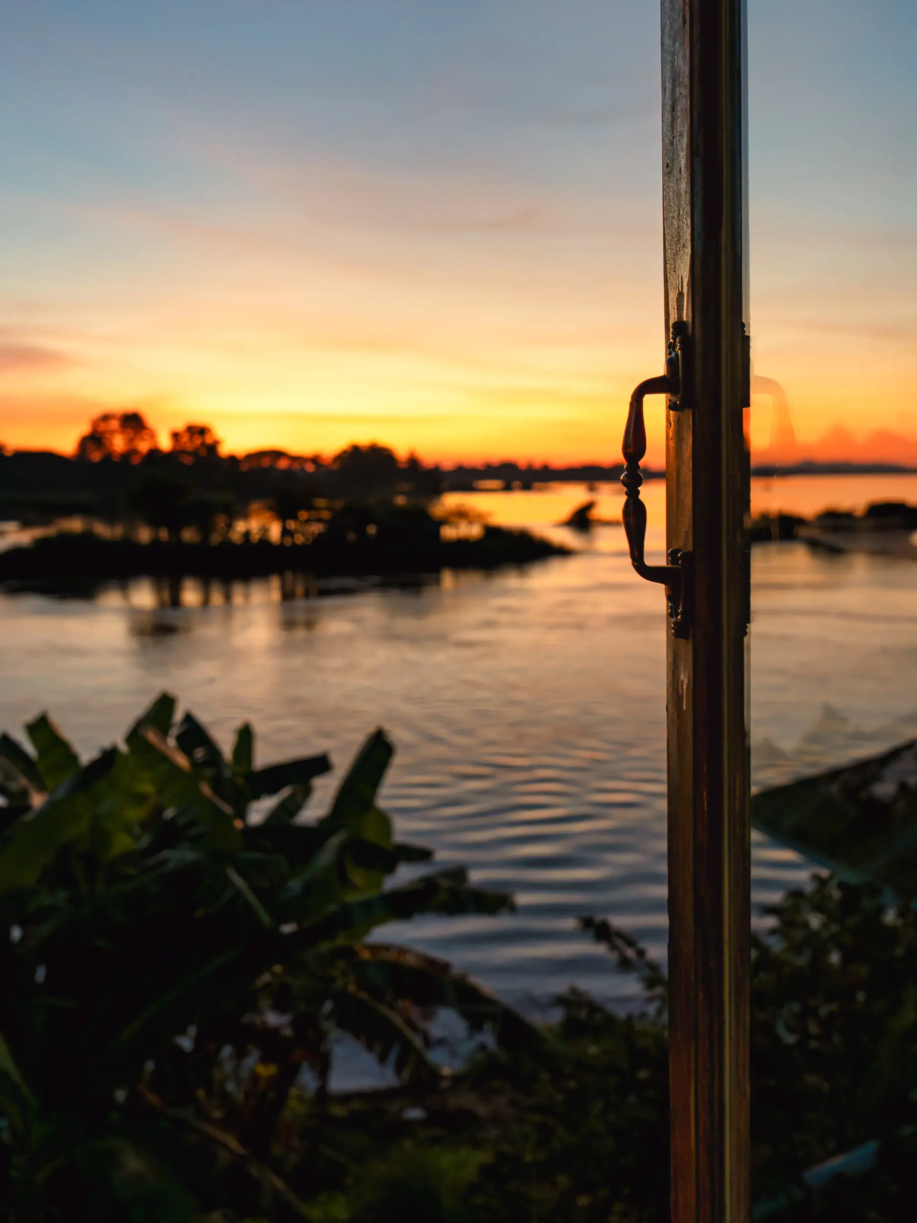 Sunset over the Mekong River with warm orange and gold hues reflected on calm evening waters.