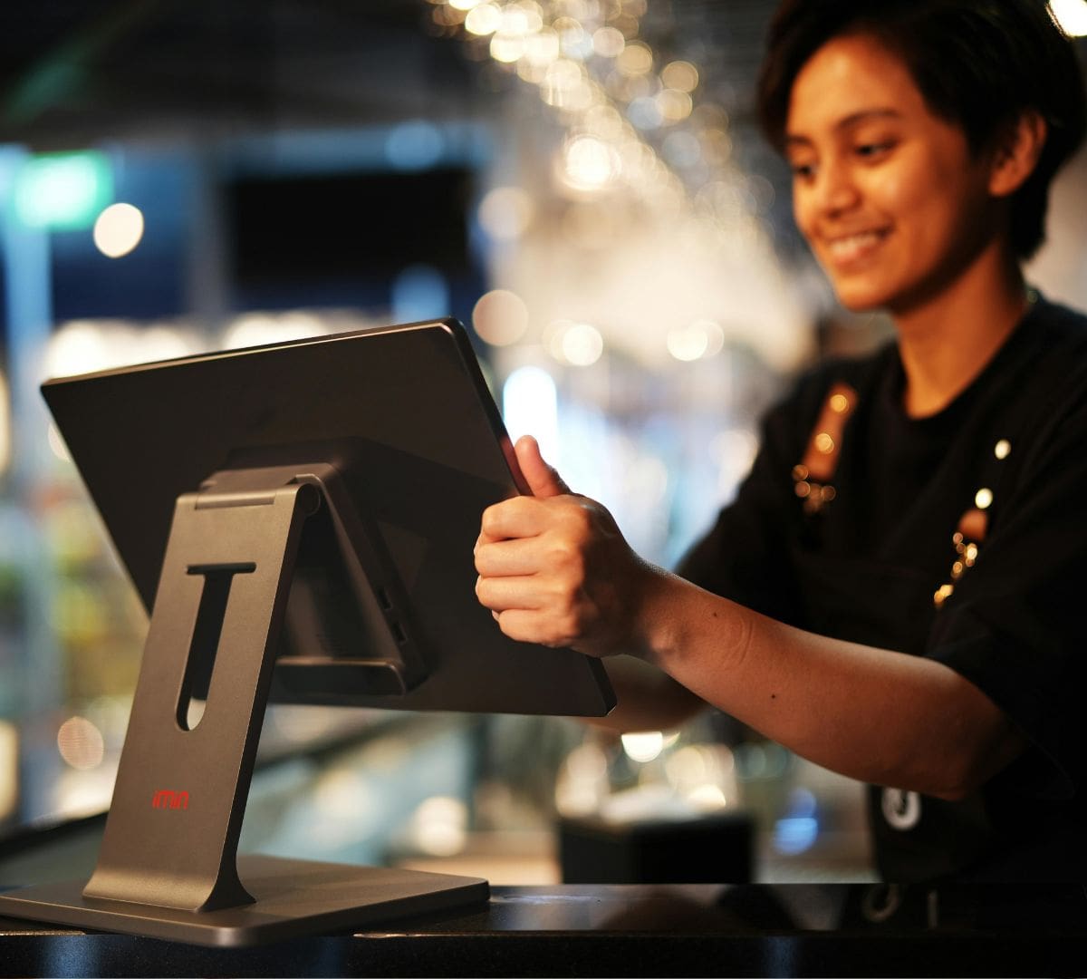 Small business employee at point-of-sale system—I-9 audit and employment verification readiness in retail or hospitality setting.