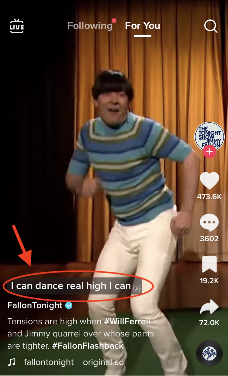 Screen shot of a TikTok from Fallon Tonight. Jimmy Fallon wears tight white pants and a green and blue striped turtleneck sweater as he sings and dances. On the bottom left, closed captions with a semi-transparent black background are circled in red with a red arrow pointing to them.