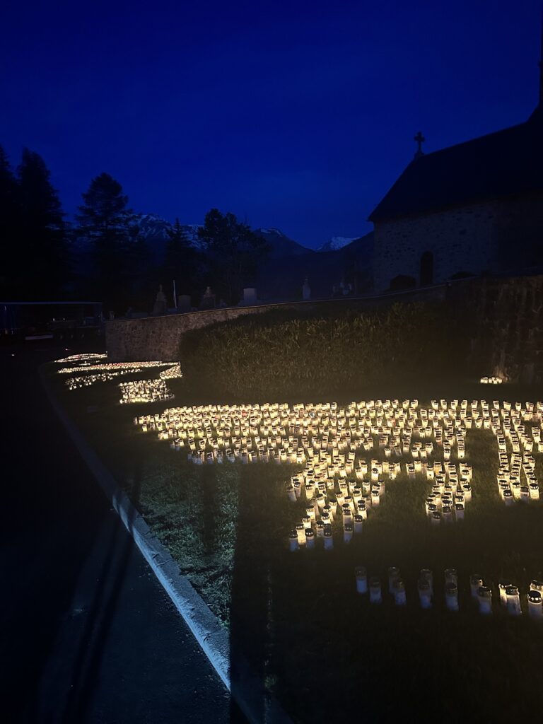 A row of lit candles sitting on top of a grass covered field
