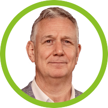 A man with grey hair and a green background