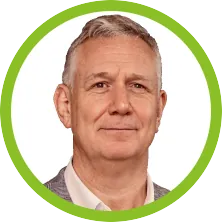 A man with grey hair and a green background