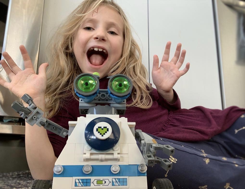 A girl posing for a picture with the robot she built