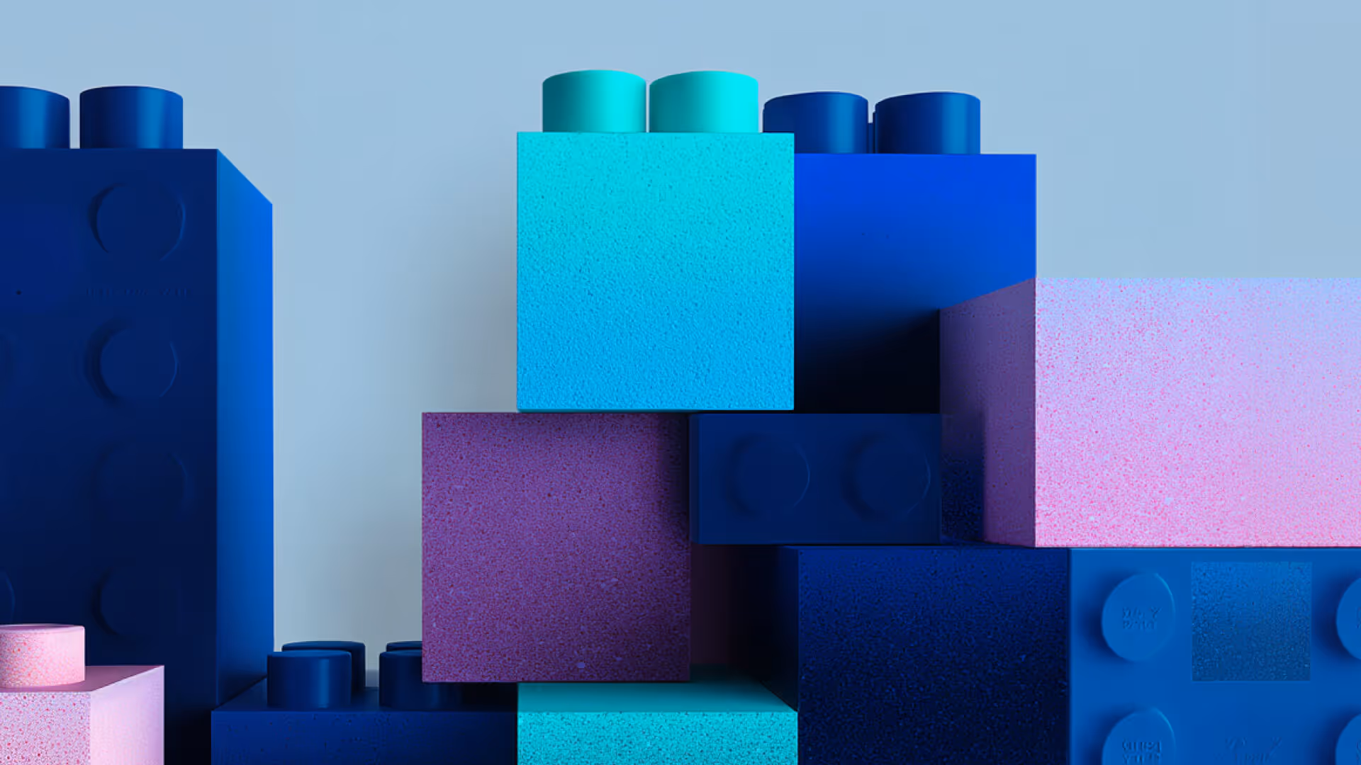 Farbige Bauklötze im LEGO-Stil in Blau, Türkis, Lila und Pink vor hellem Hintergrund.