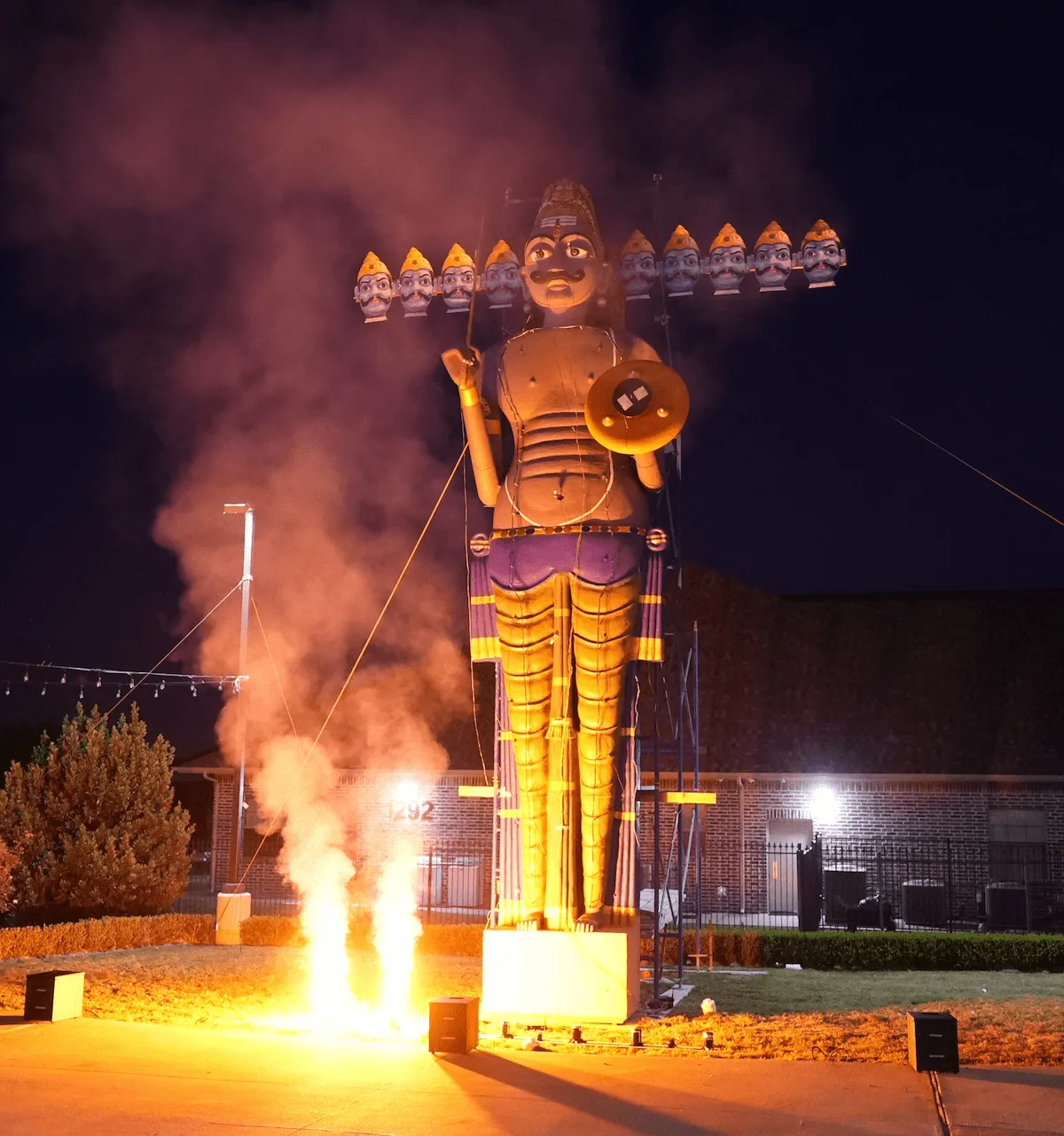 A tall Ravan effigy beside rising flames during the evening Ravan Dahan.