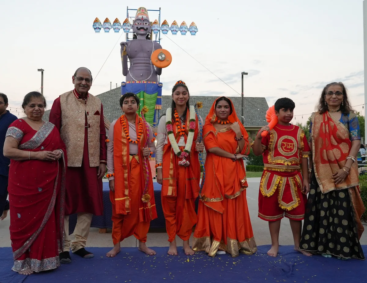 A group portrait of young cultural performers with their families beside the Ravan effigy.