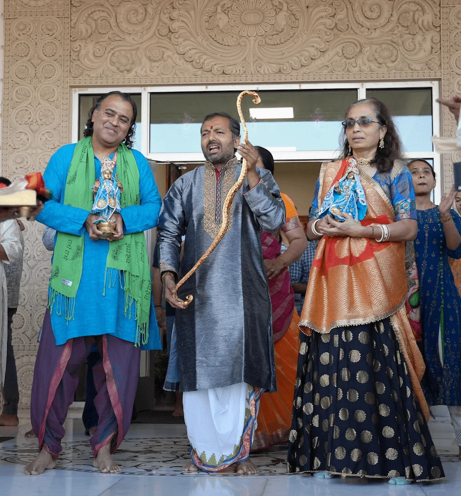 Community members holding a ceremonial bow at the carved temple entrance.