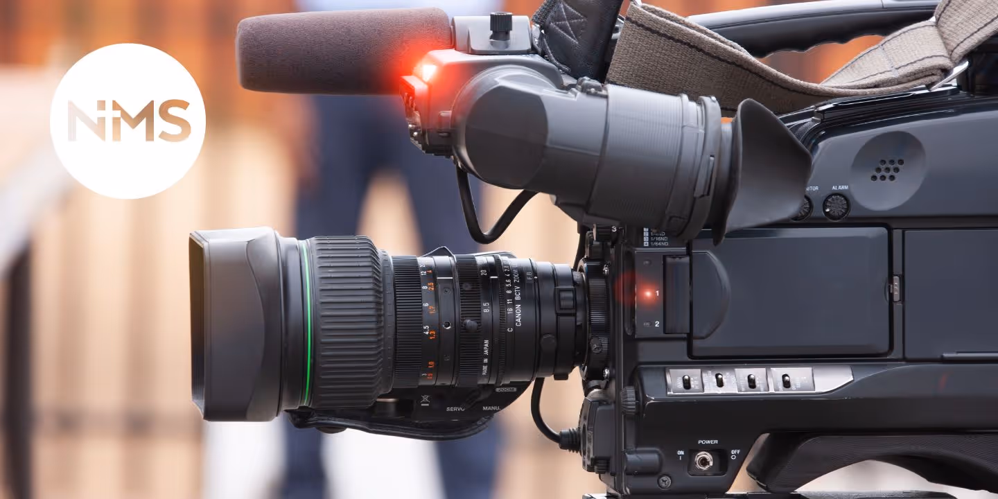 Bildet viser et kamera og NMS-logoen. Bildet er til landingsside for infosending for frivillige