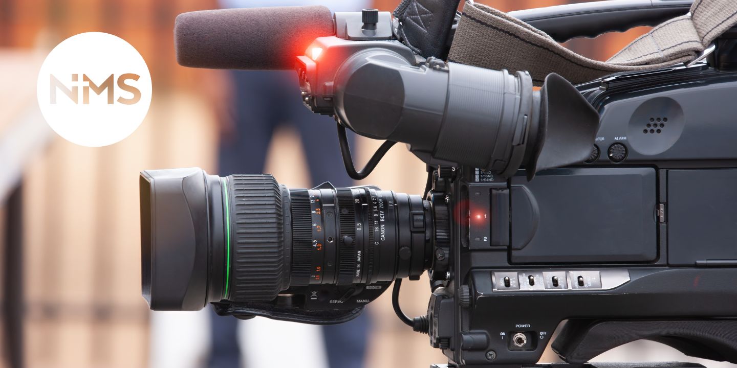 Bildet viser et kamera og NMS-logoen. Bildet er til landingsside for infosending for frivillige