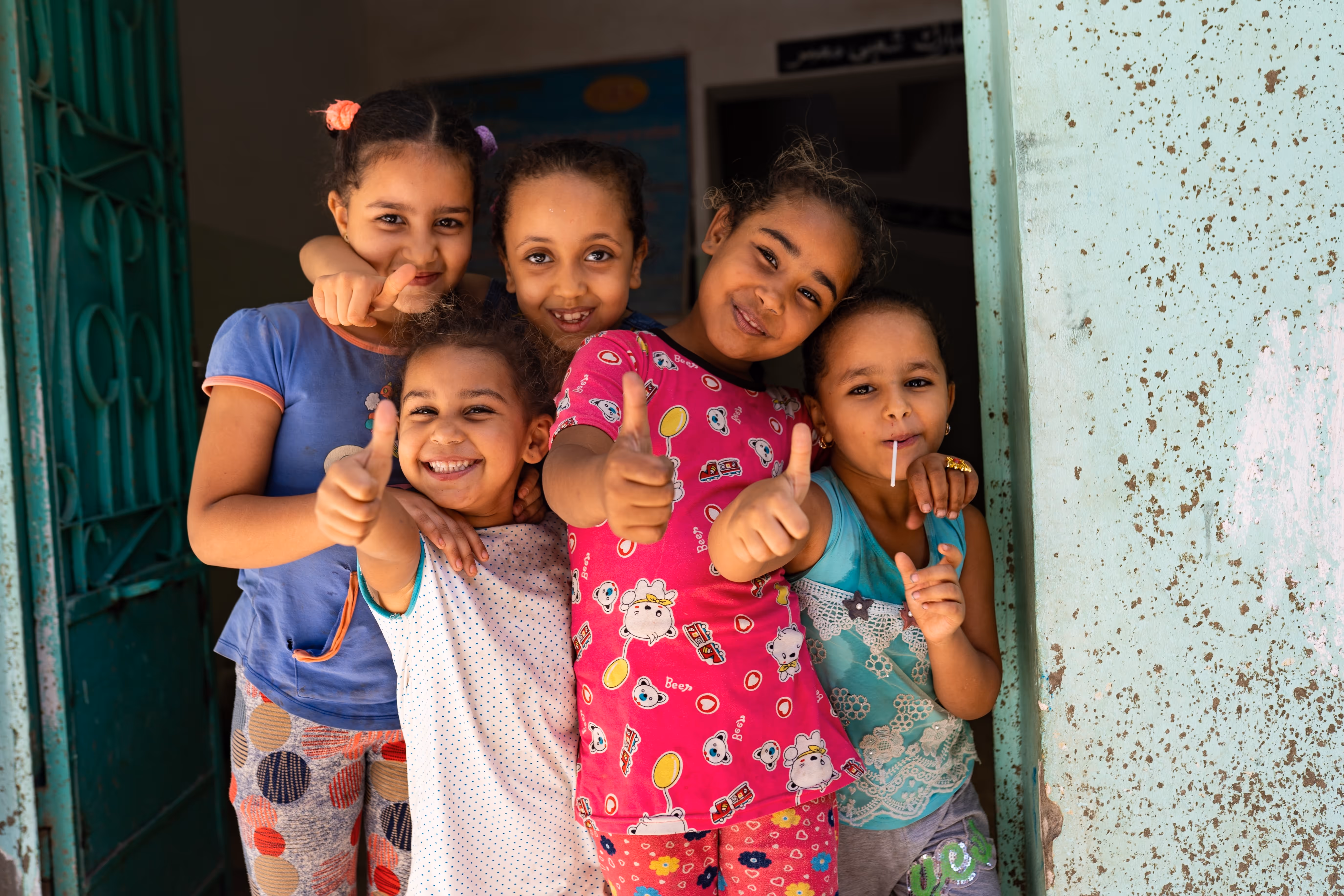 Bildet viser fem personer som står i en døråpning og gir tommel opp til kameraet