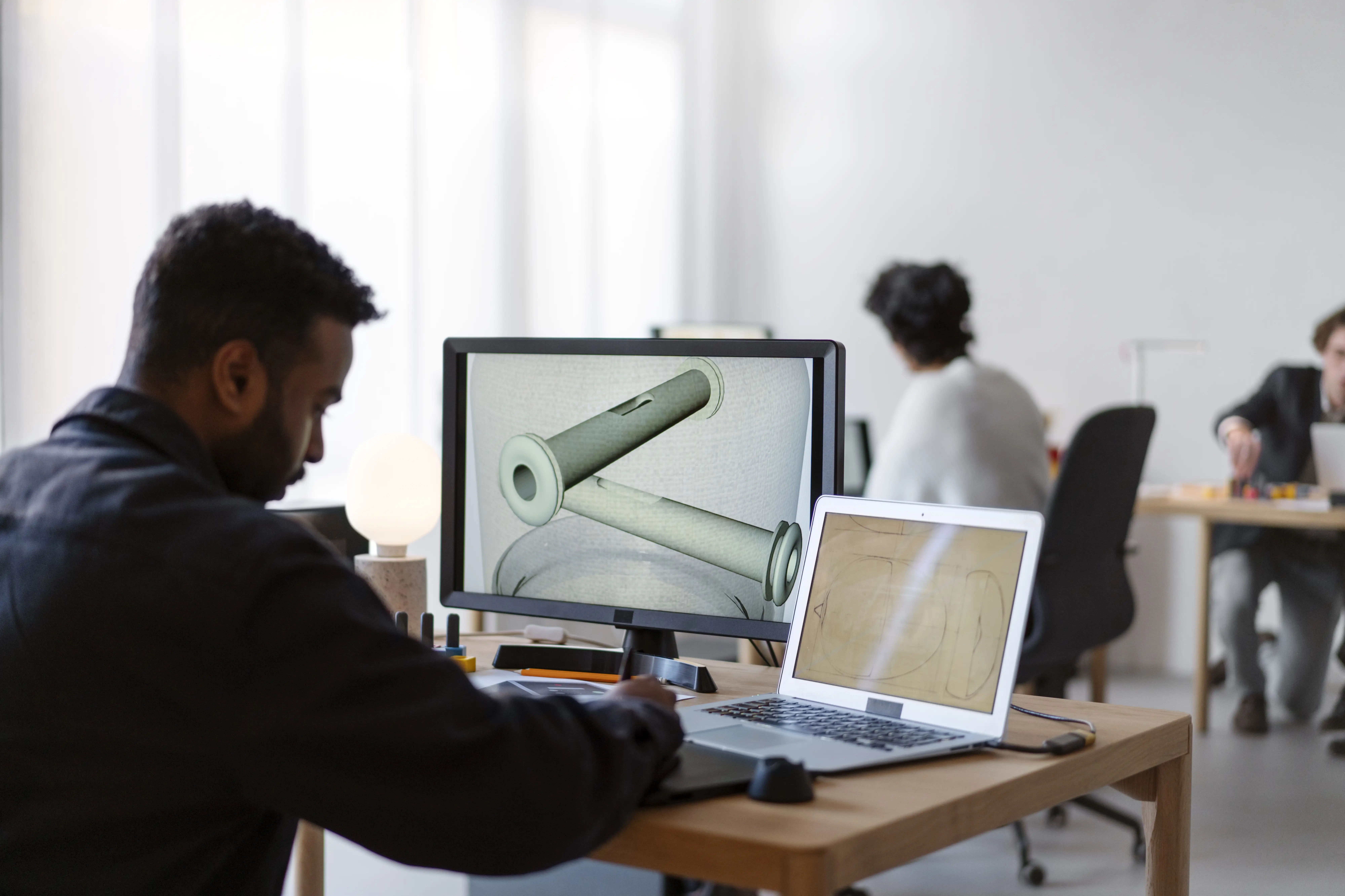 Design team collaborating on CAD models at desktop workstations.