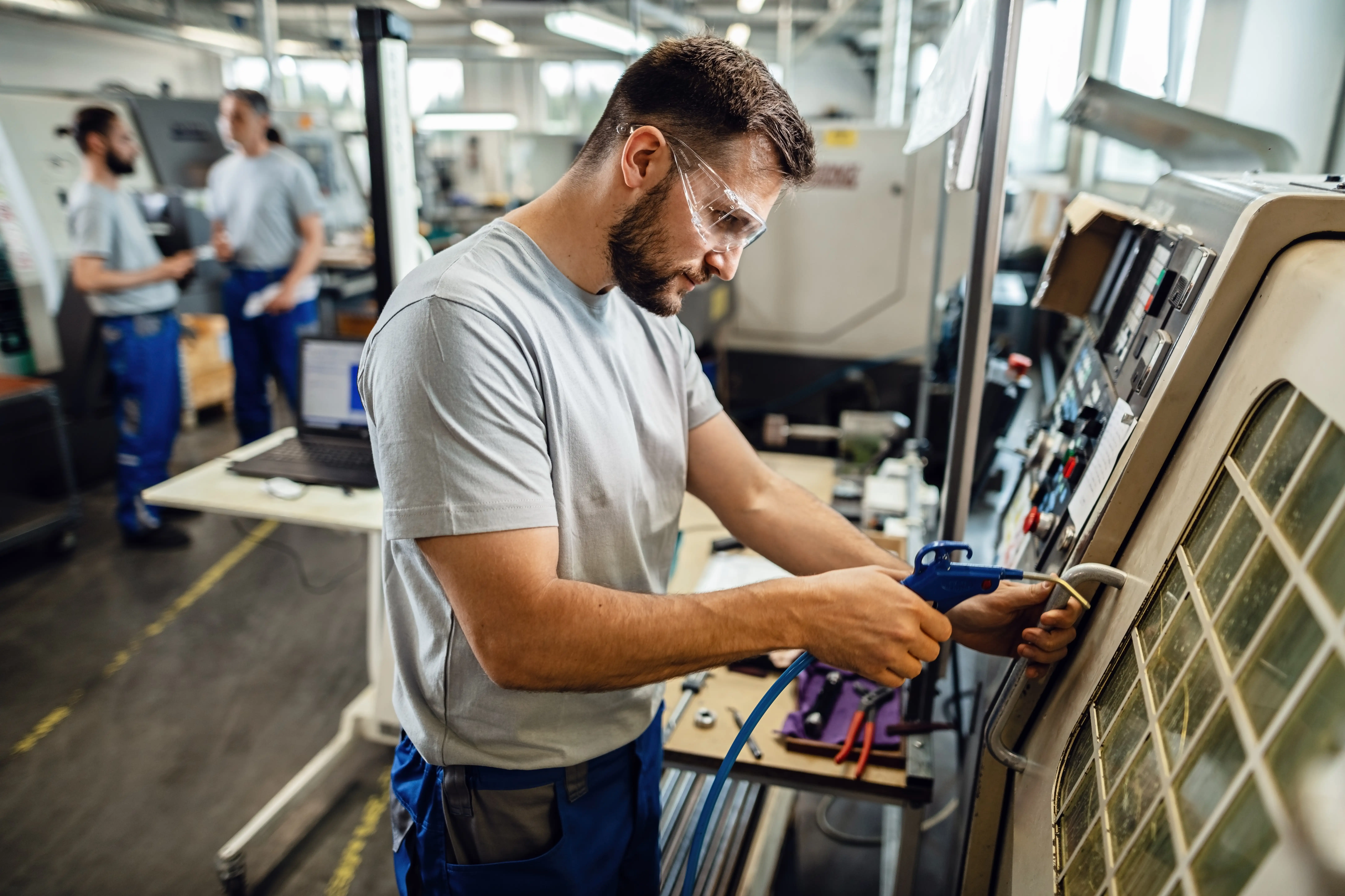 oung engineer operating a CNC control panel in a modern factory.