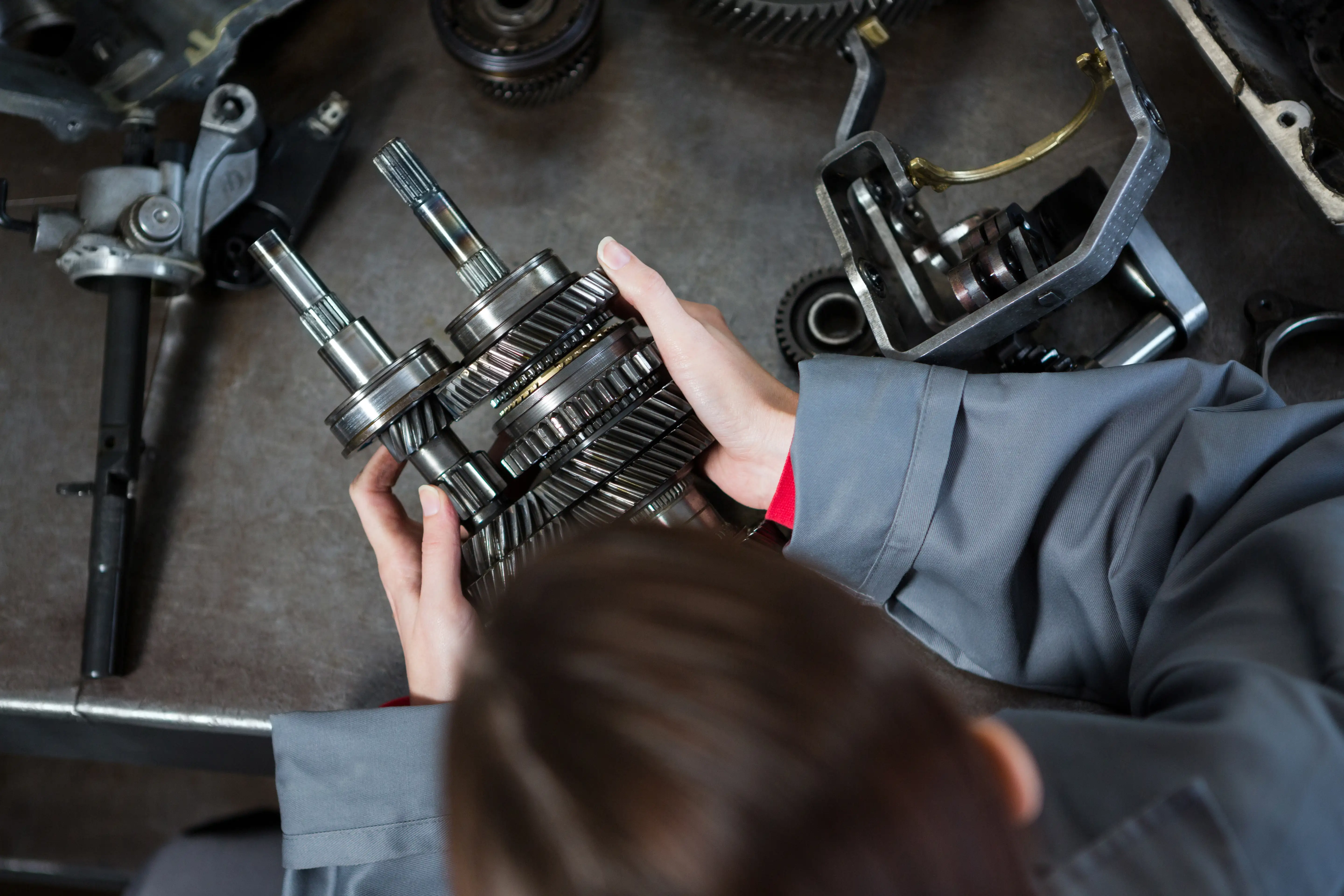 Female engineer assembling or inspecting an intricate mechanical part.