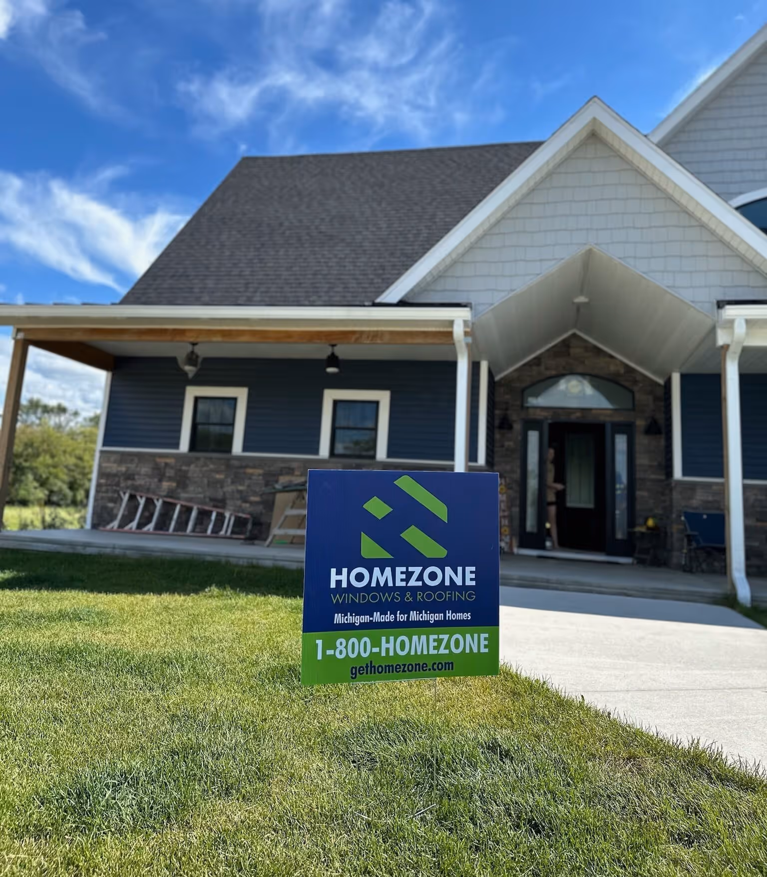 Homezone Windows & Roofing sign placed in front of a Michigan home, marking a completed or ongoing window and roofing project – trusted local contractor for Michigan-made solutions.