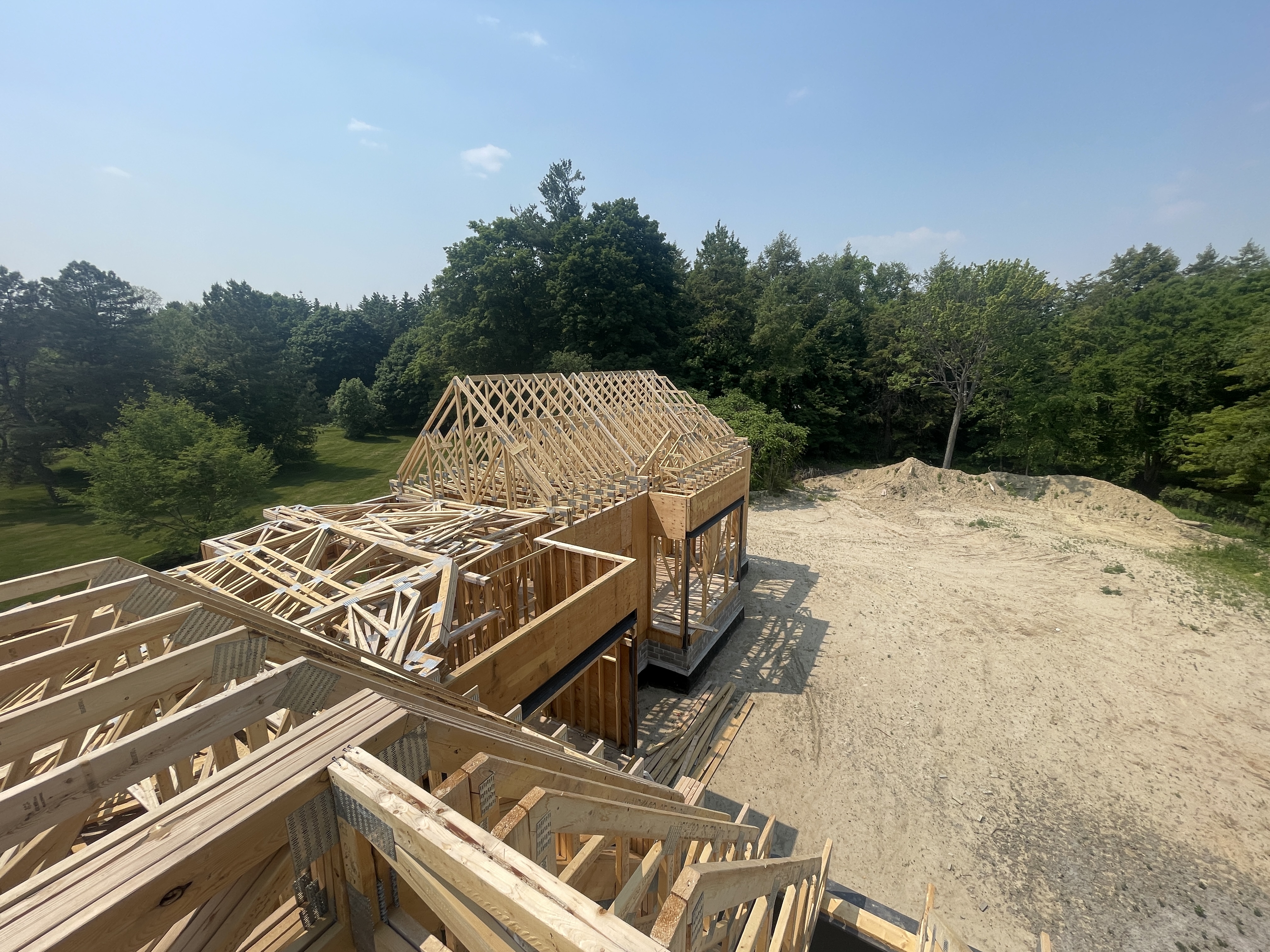 Framing crew installing complex roof trusses on a custom bungalow in King City