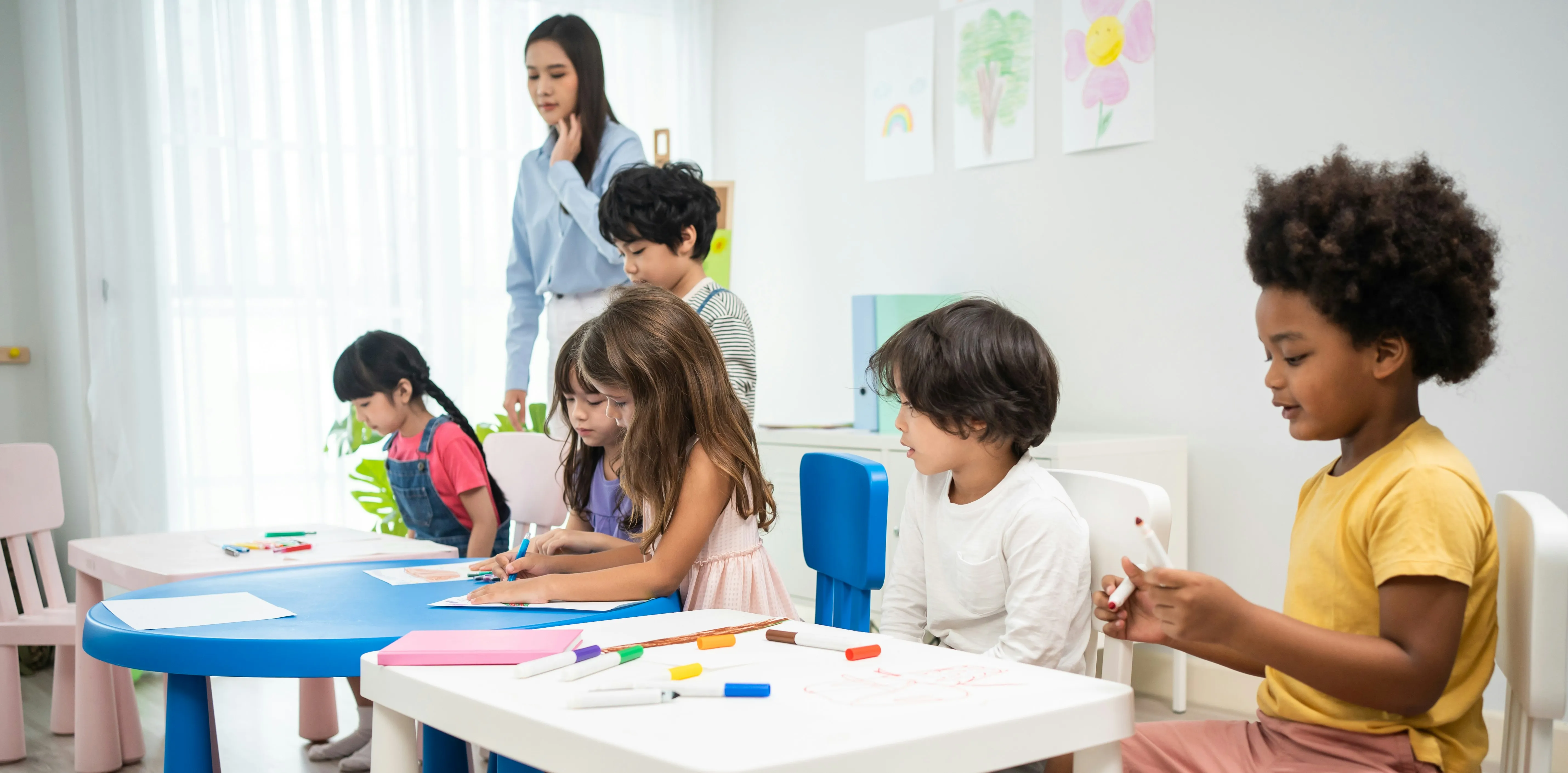 A Teacher leads a diverse group of young students in a bright, engaging classroom during BridgeUSA Programs (J-1 Visa).