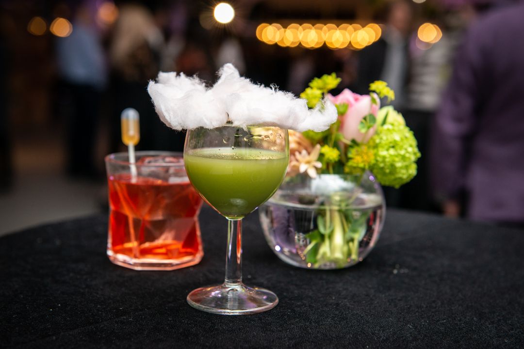 pahar cu cocktail pe o masa cu o vaza cu flori