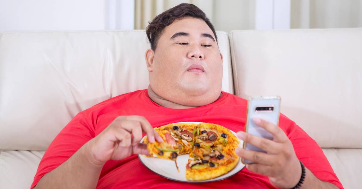 Homme mangeant une pizza en mode sédentaire, illustration des idées reçues sur la pizza et la prise de poids.