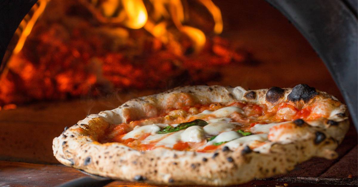 Pizza napolitaine en train de cuire au feu de bois, résultat d’une bonne fermentation de la pâte