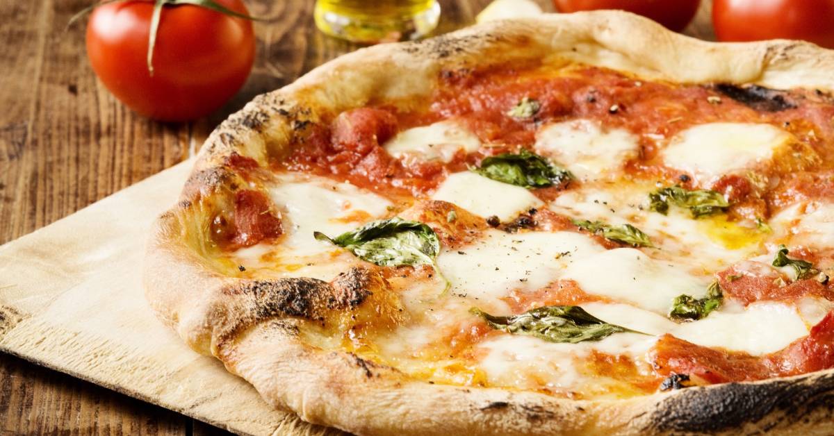 Pizza Margherita maison avec sauce tomate, mozzarella fondante et feuilles de basilic frais, cuite au four à bois pour une croûte croustillante et dorée. Exemple de pizza saine et équilibrée."
