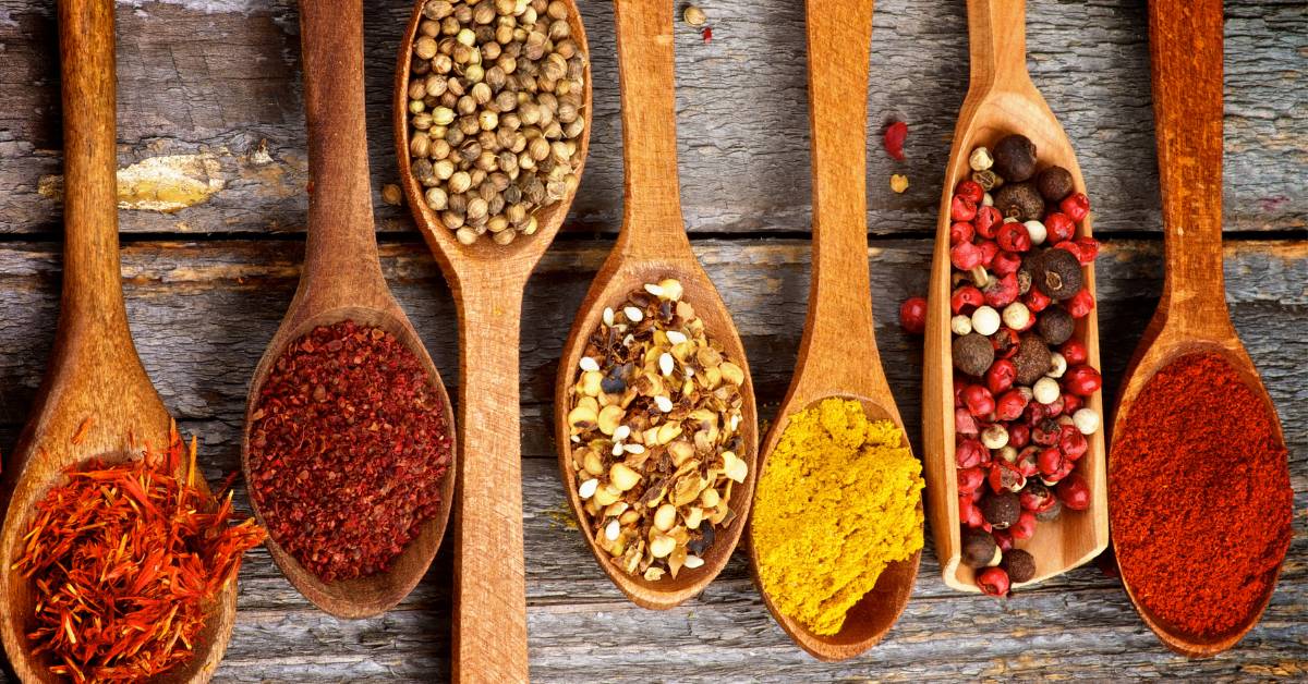 Assortiment d’épices en cuillères en bois : piment rouge, poivre noir, coriandre, curcuma, graines de fenouil et poivre rose. Idéal pour rehausser les saveurs d’une pizza maison de manière naturelle et healthy