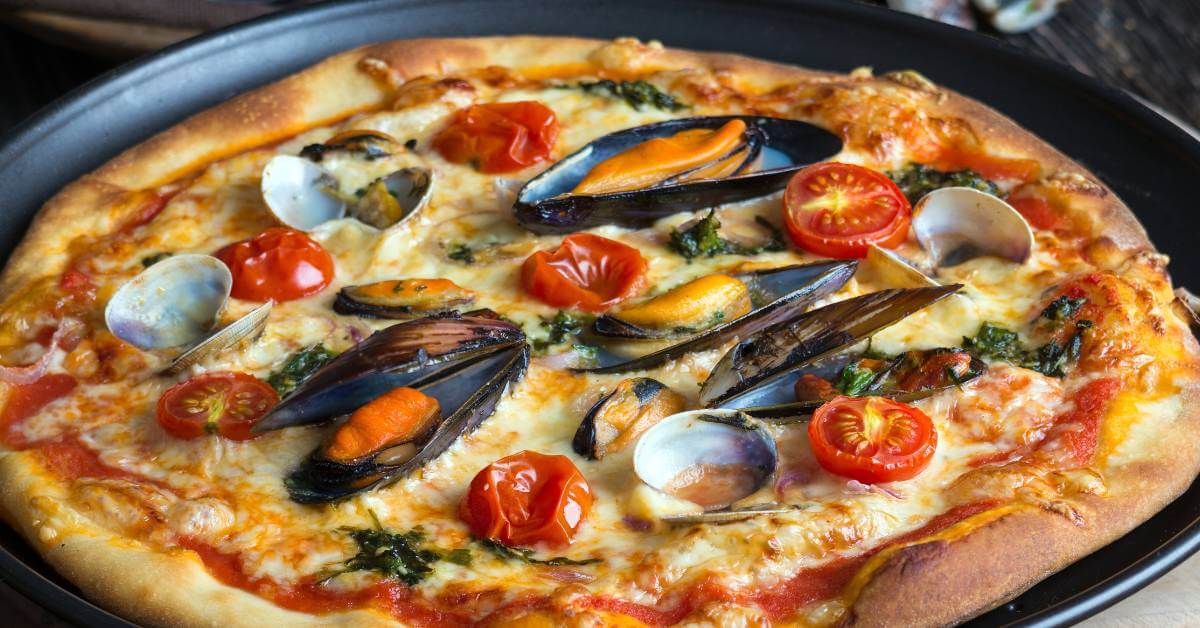 Cette pizza aux moules juteuses, tomates cerises éclatées et coquillages fondants est un vrai voyage en une bouchée ! La croûte dorée, le fromage filant et l’explosion d’arômes marins… Qui oserait résister ?