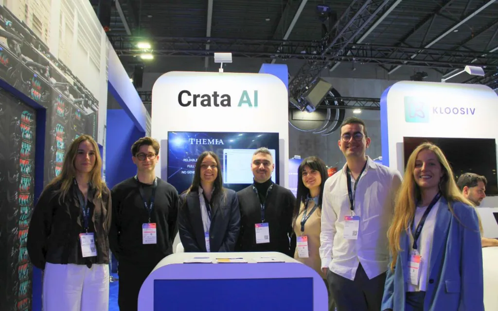 Seven people standing at Crata AI booth at a tech event, smiling and wearing badges.