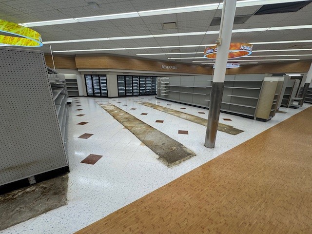 Partially cleared Rite Aid store with gondola shelving and rows of commercial coolers with remote compressors, retail pharmacy fixtures for liquidation.