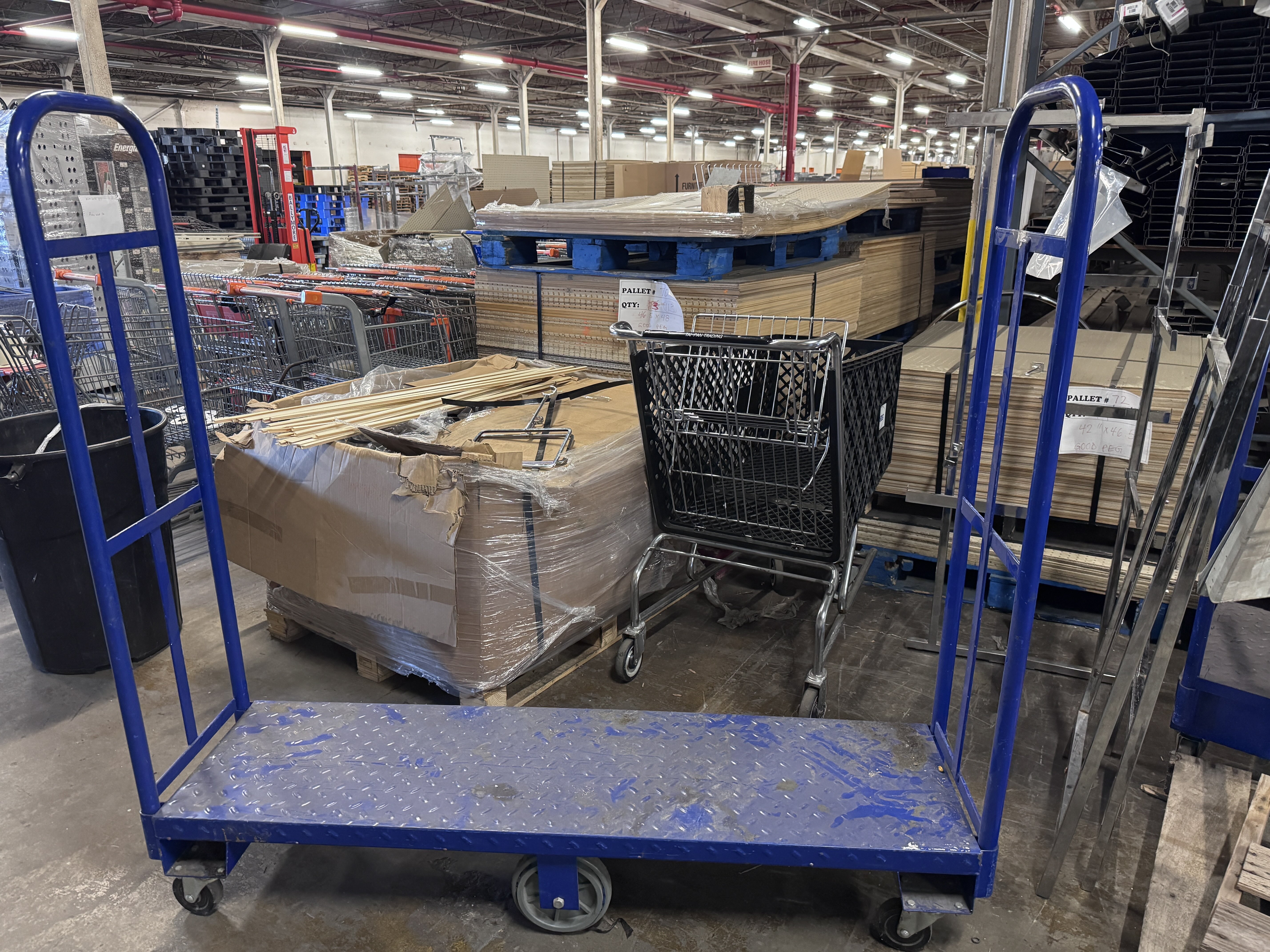 Blue commercial platform stock cart with heavy-duty wheels used for retail stocking and warehouse material handling. Industrial U-boat cart available from Mid-America Store Fixtures.