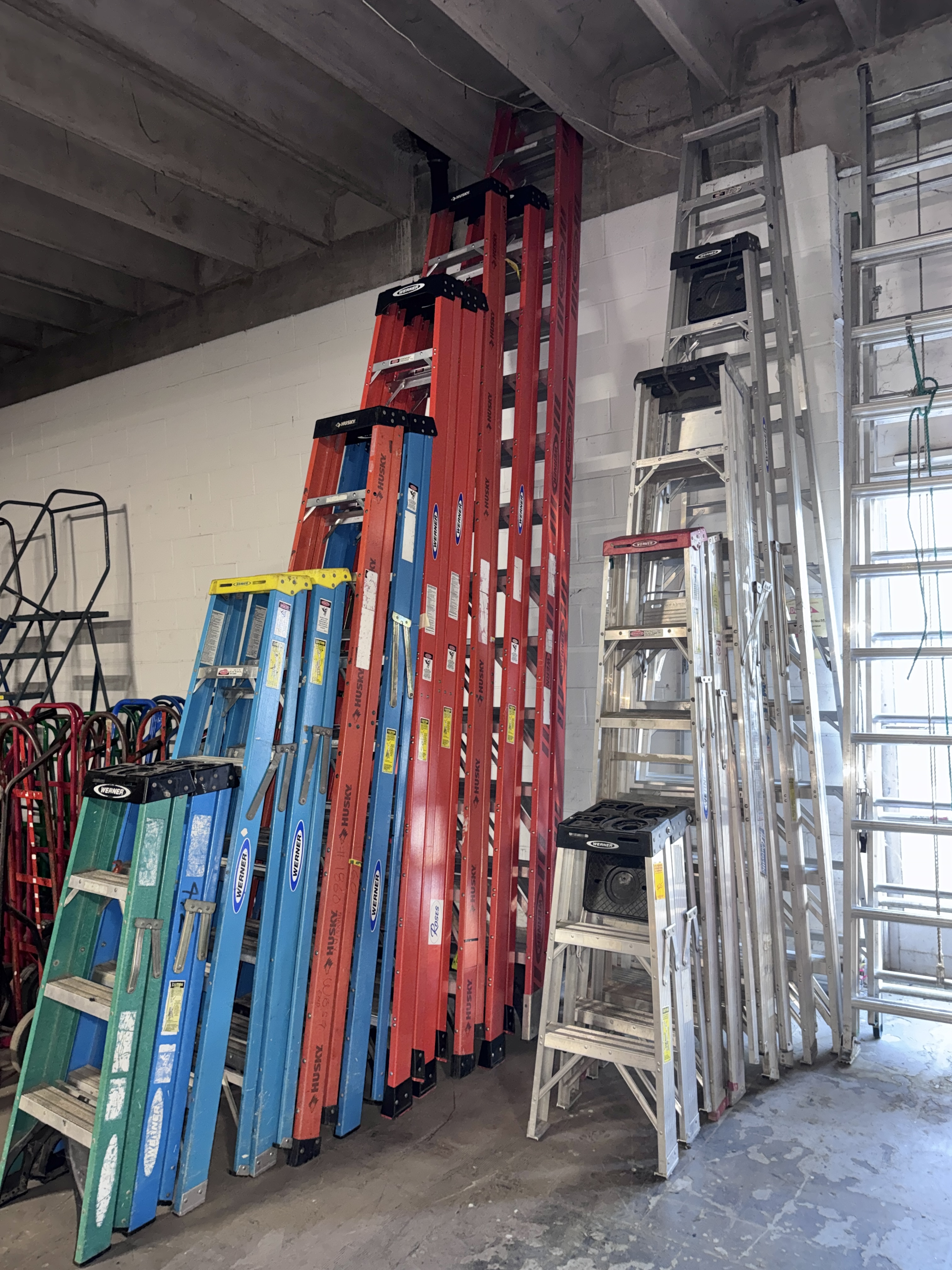 Large assortment of commercial fiberglass and aluminum A-frame and extension ladders in multiple heights for warehouse, retail, and industrial use. High-quality ladders available from Mid-America Store Fixtures.