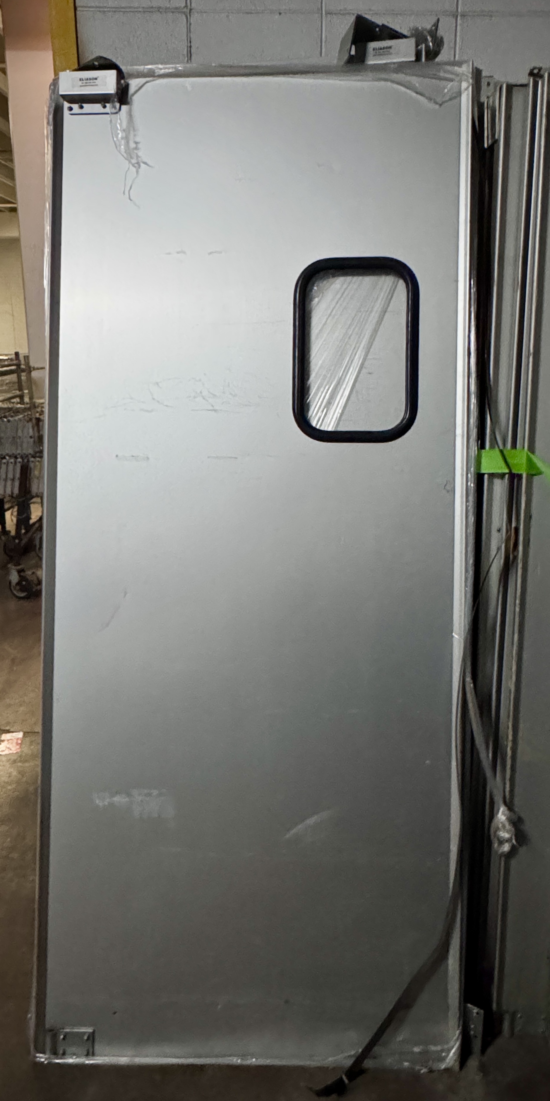 Commercial stainless steel swinging door with inspection window, suitable for grocery stores, restaurants, and warehouse backroom access. Industrial swinging doors available from Mid-America Store Fixtures.