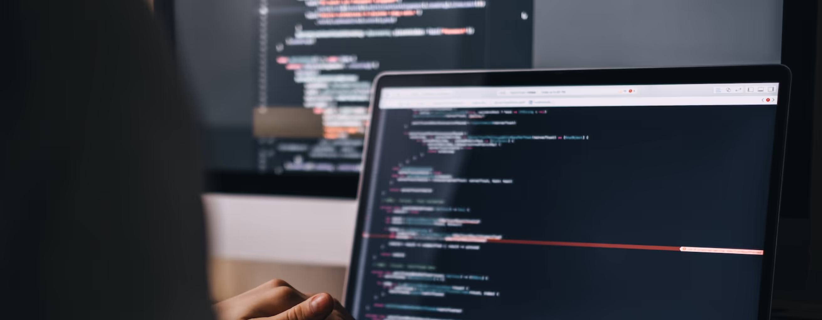 Illustrative image of a Macbook with external display, displaying active development of software