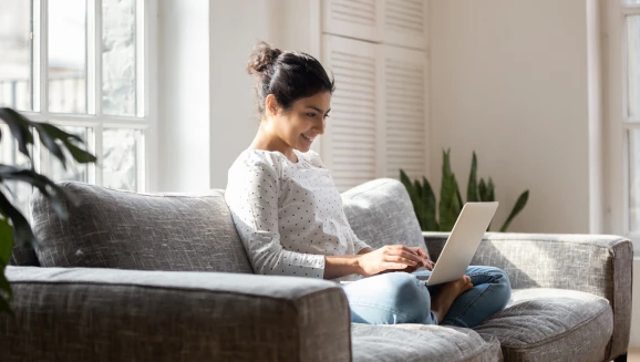 A young woman researching down payment assistance programs from her laptop.