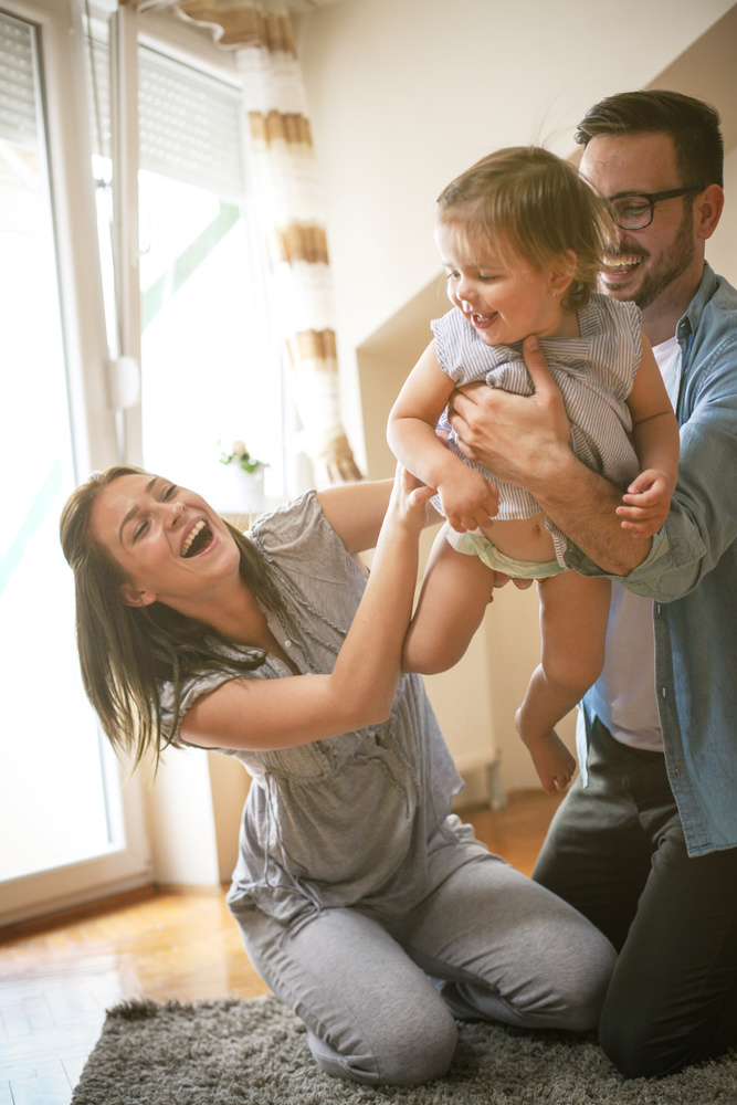 A father hanging art with his children in the new home they purchased with a fixed rate mortgage.